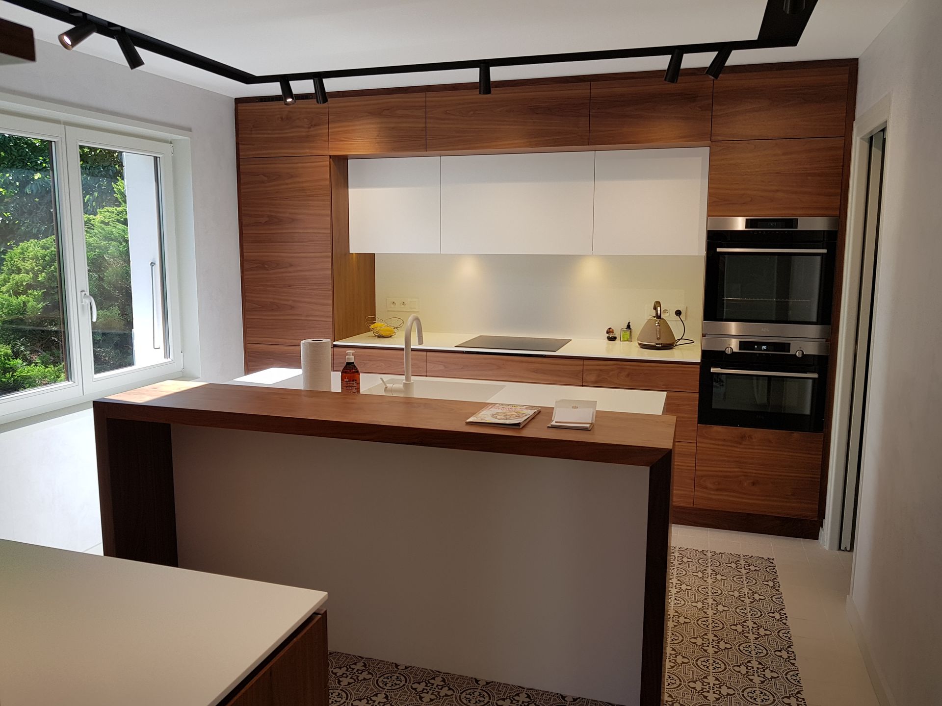 Cuisine moderne avec armoires en bois, comptoirs blancs et îlot central.