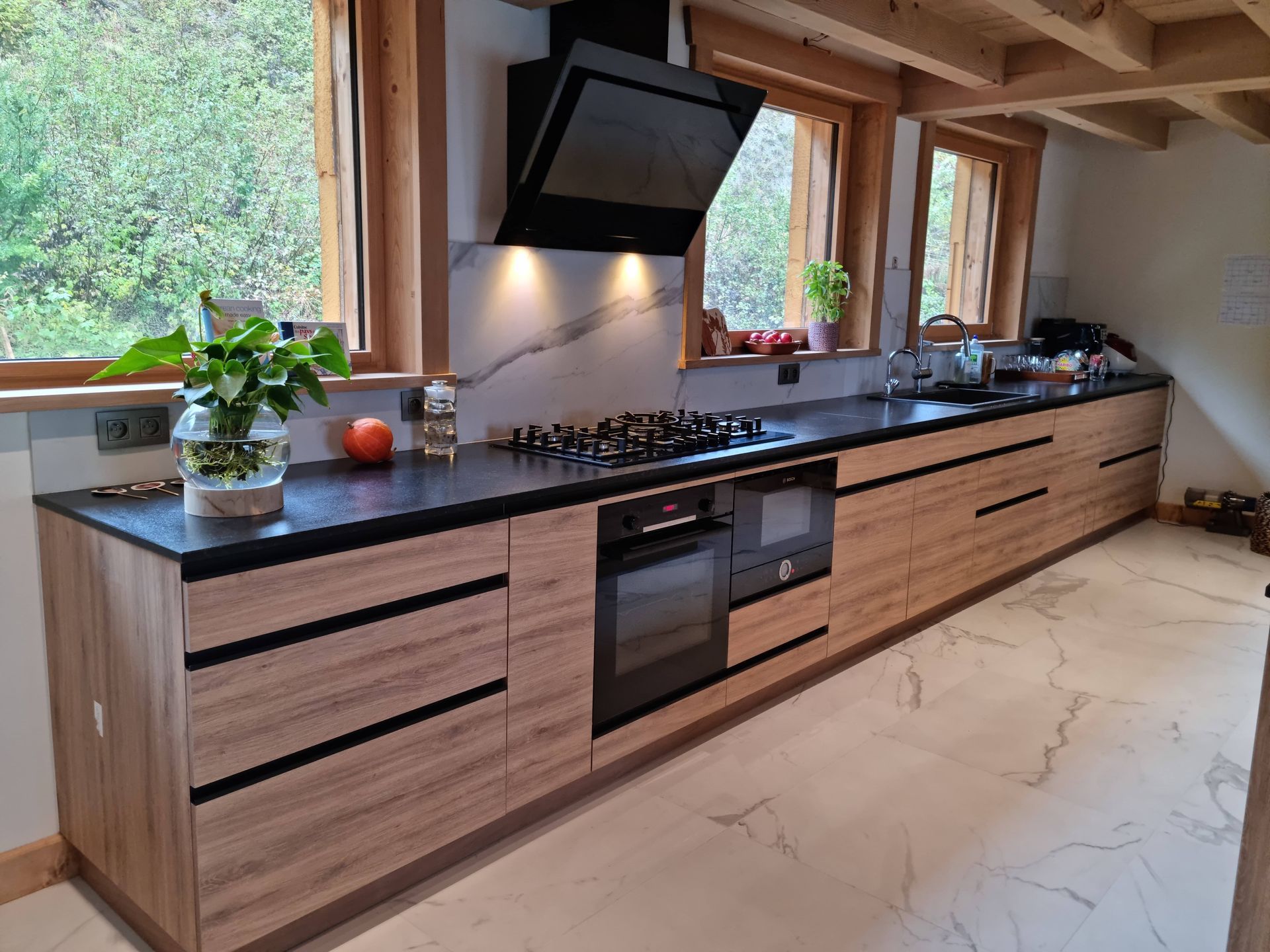 Cuisine moderne avec armoires en bois, comptoirs noirs et électroménagers.