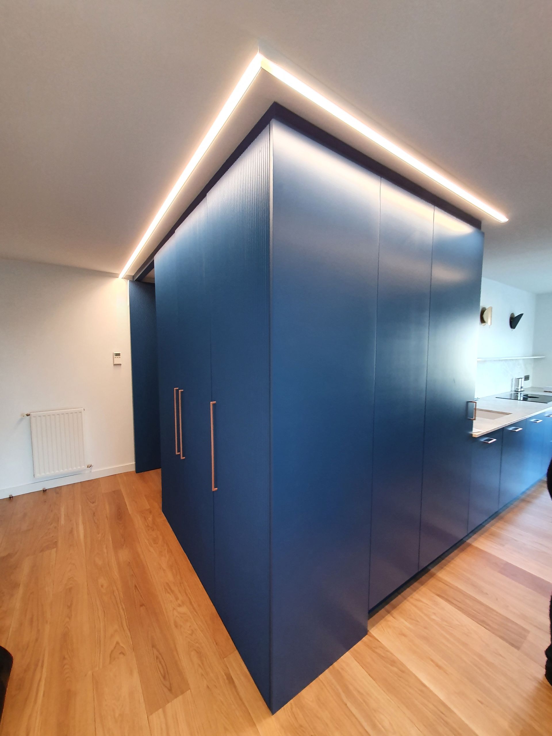 Cuisine moderne avec meubles bleus et éclairage intégré, et parquet.