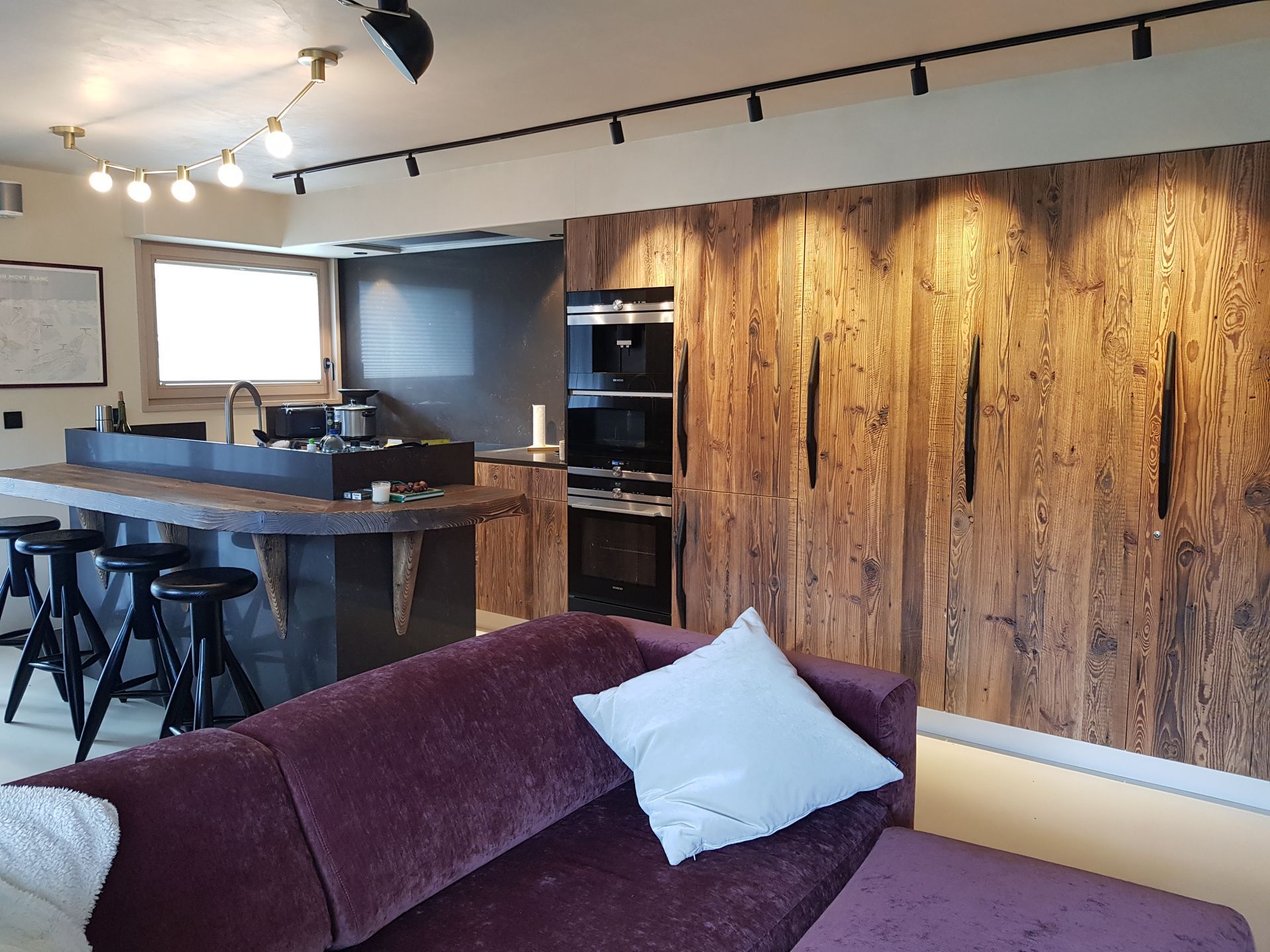 Cuisine moderne avec lambris, canapé violet et appareils électroménagers noirs.