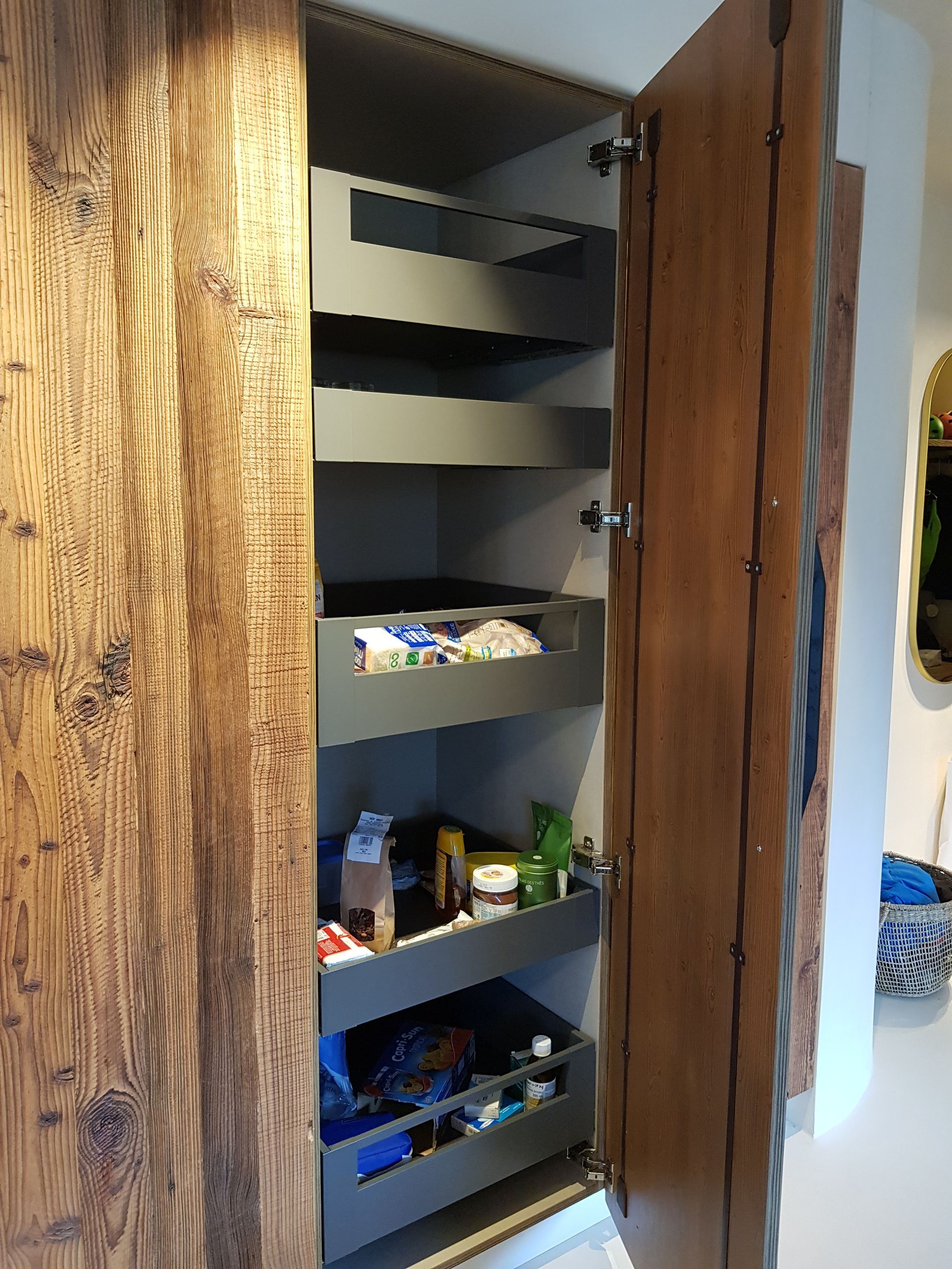 Armoire de rangement ouverte avec portes en bois et étagères coulissantes pour les aliments.