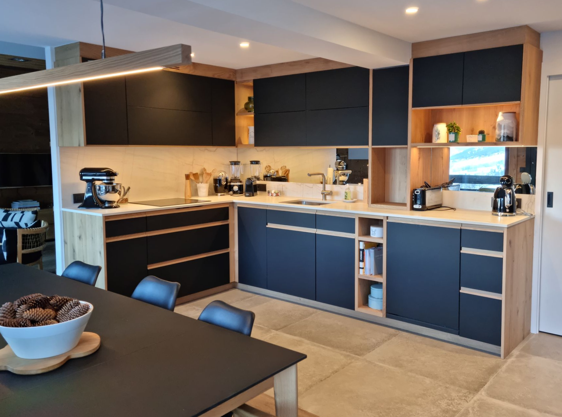 Cuisine moderne avec armoires noires, accents de bois et table à manger.