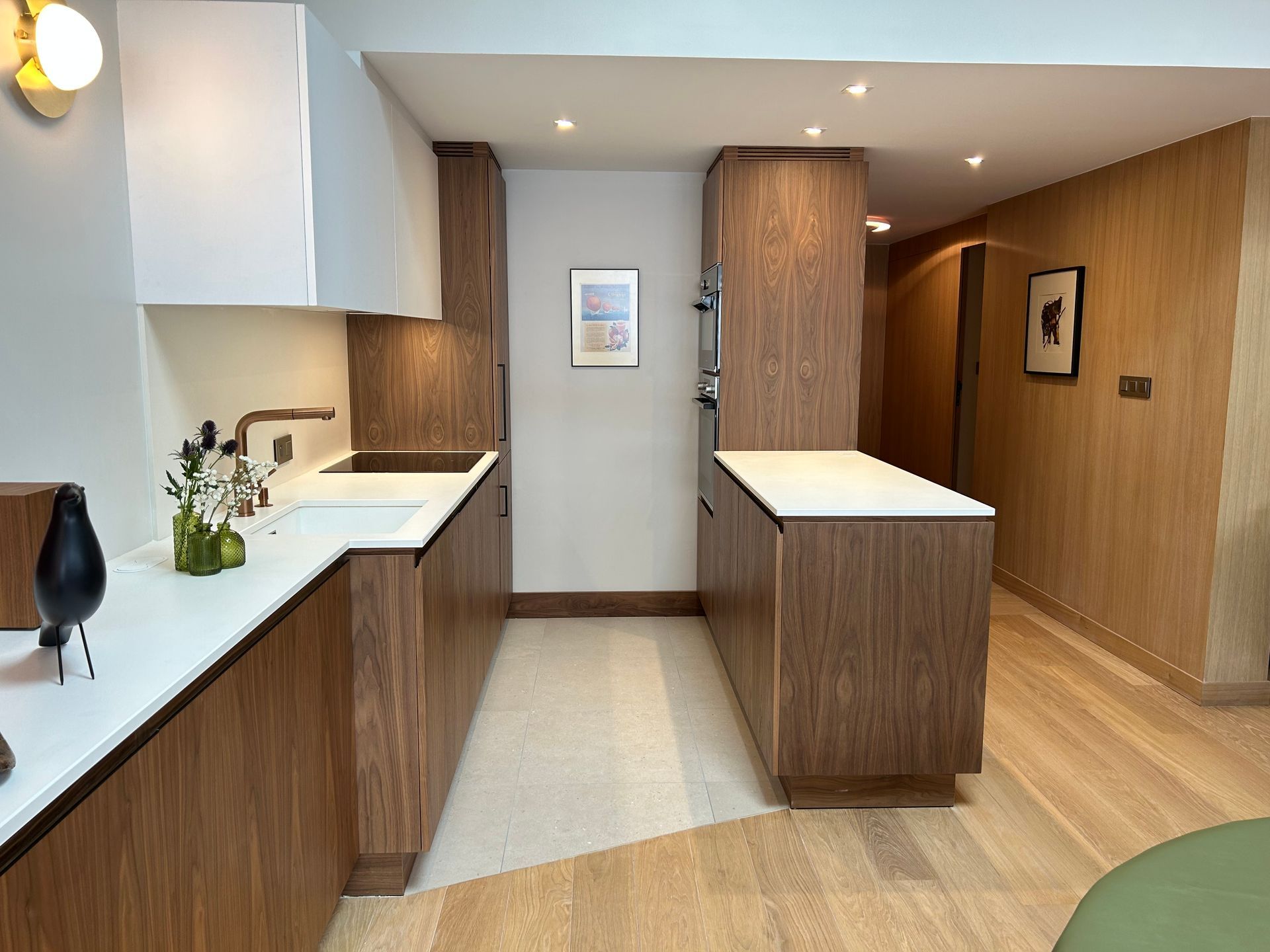 Cuisine moderne avec armoires en bois, comptoirs blancs et petit îlot.