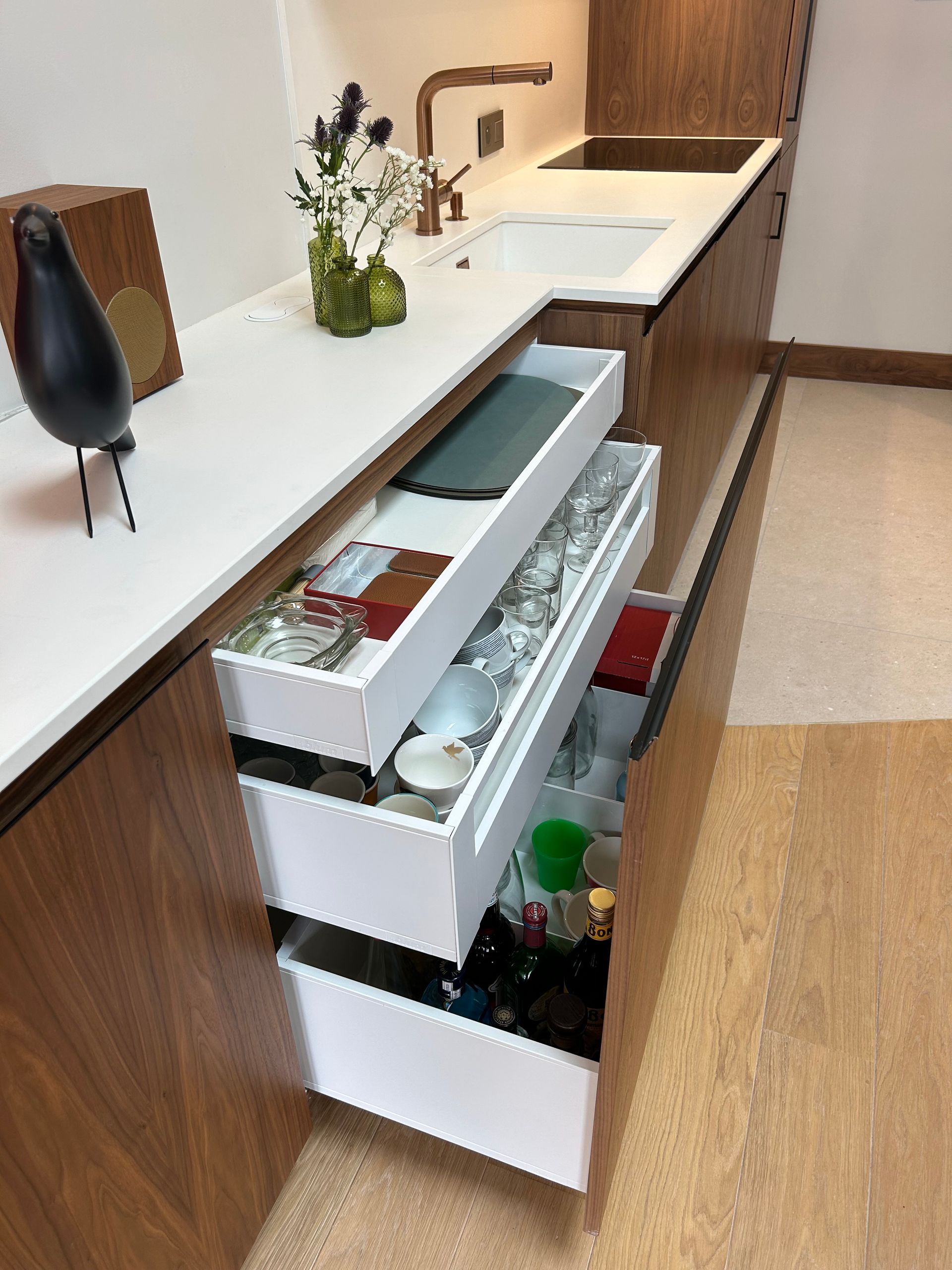 Cuisine moderne avec tiroirs ouverts. Plans de travail blancs, armoires en bois et ustensiles de cuisine assortis.