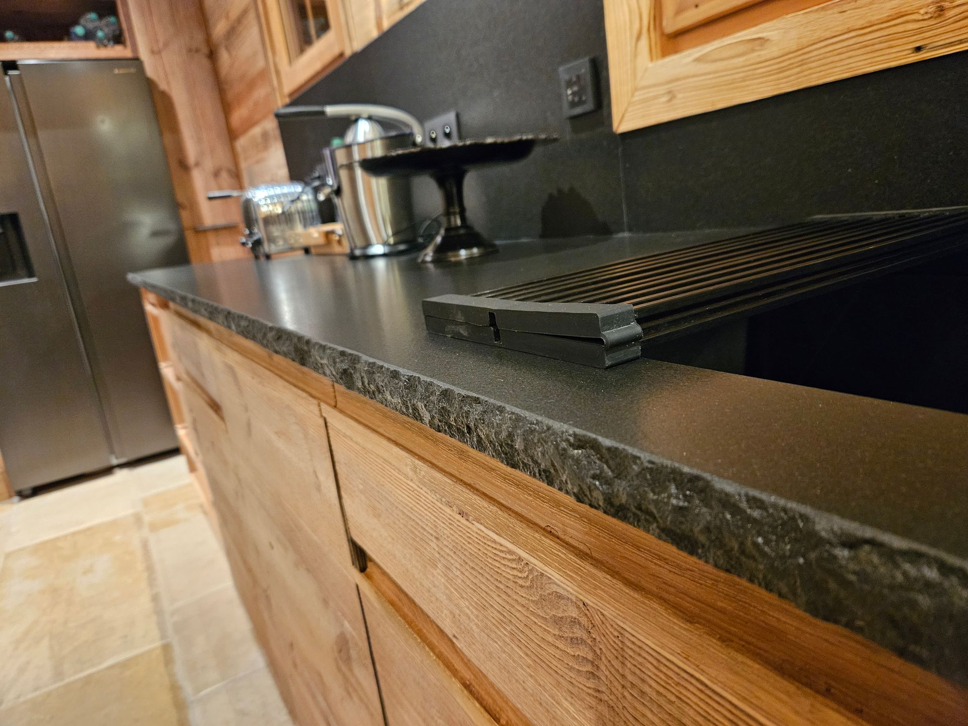 Cuisine équipée de meubles en bois, d'un plan de travail foncé et d'appareils électroménagers en acier inoxydable.