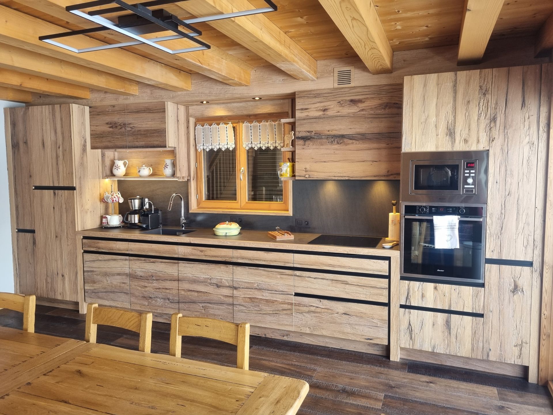 Cuisine en bois avec placards, four, micro-ondes et table à manger.