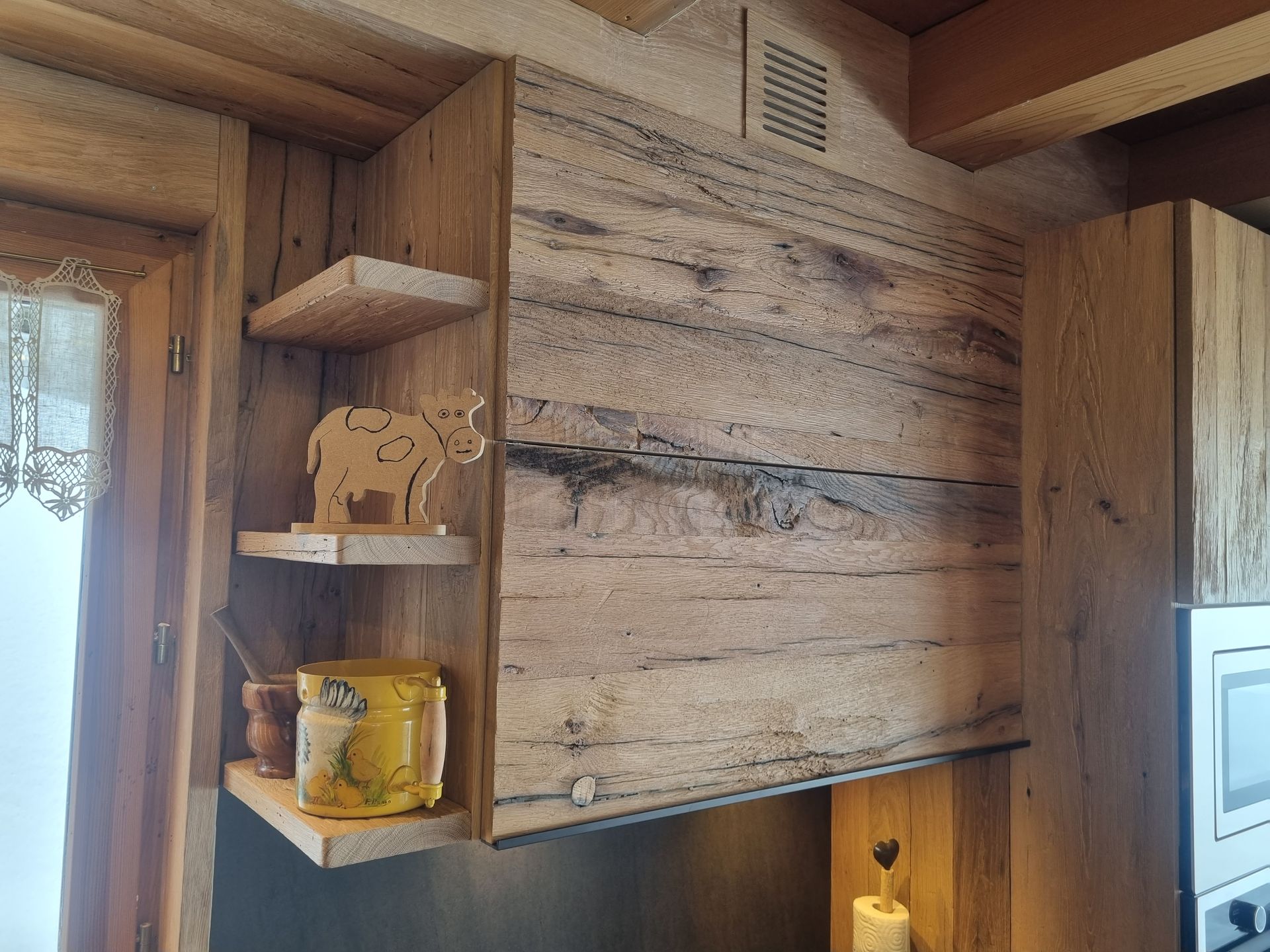 Coin cuisine rustique avec placards et étagères en bois, et un rhinocéros décoratif en bois.