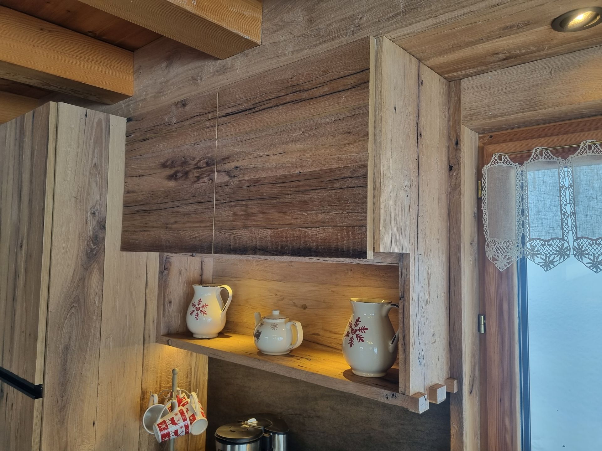 Meuble de cuisine en bois avec une étagère contenant des pichets en céramique et une théière.