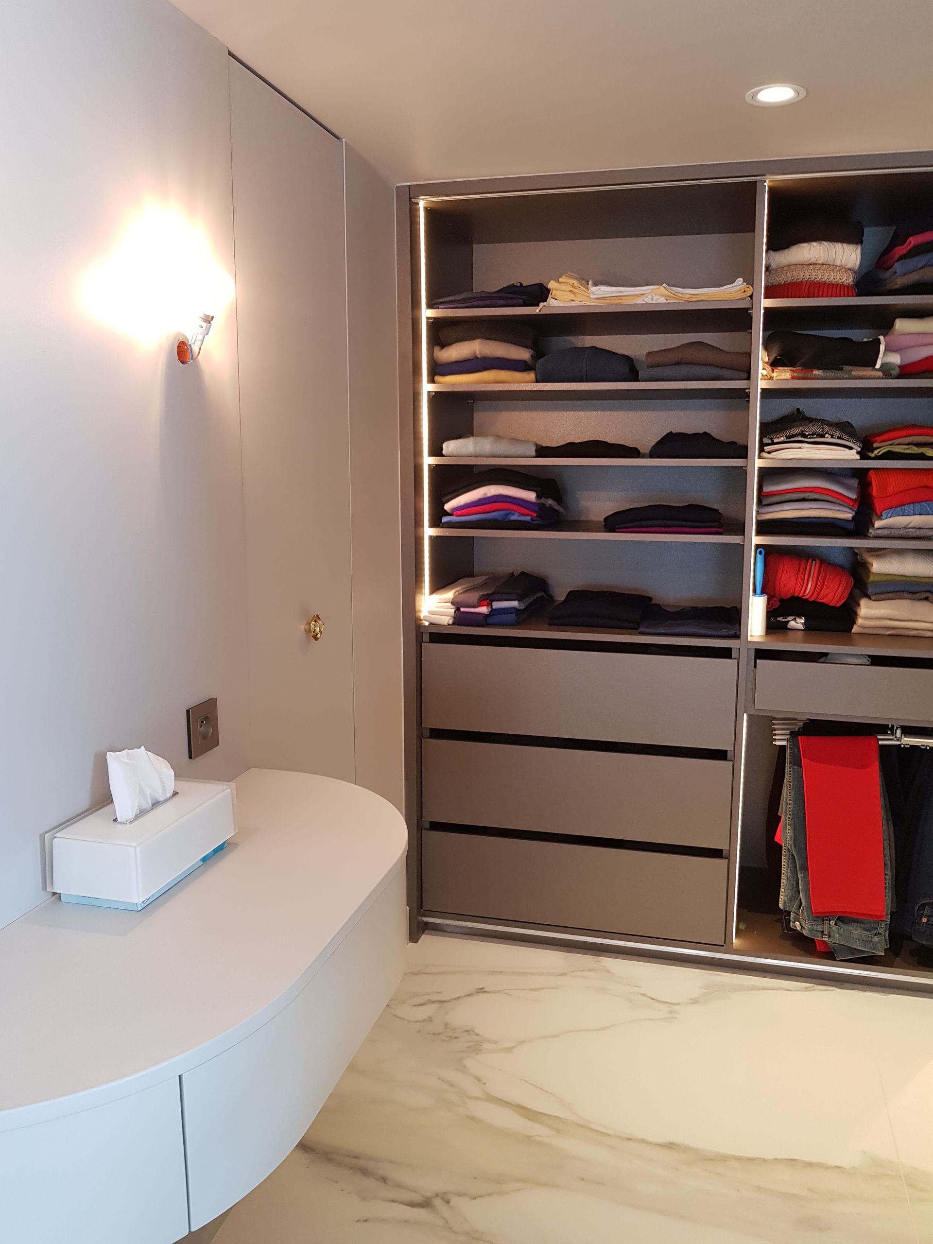 Un dressing avec beaucoup de vêtements sur les étagères