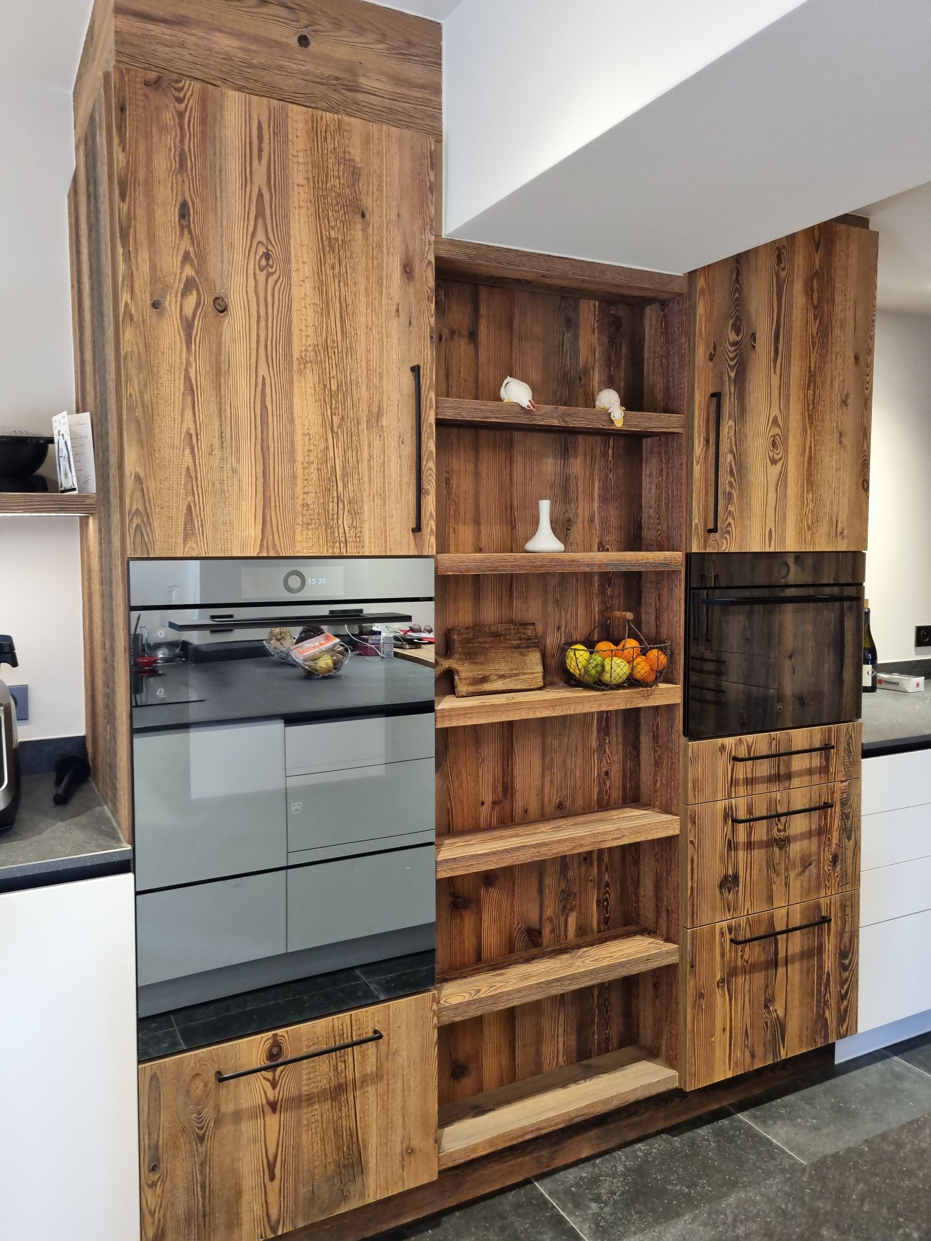 Meubles de cuisine en bois avec fours intégrés et étagères ouvertes pour le rangement.