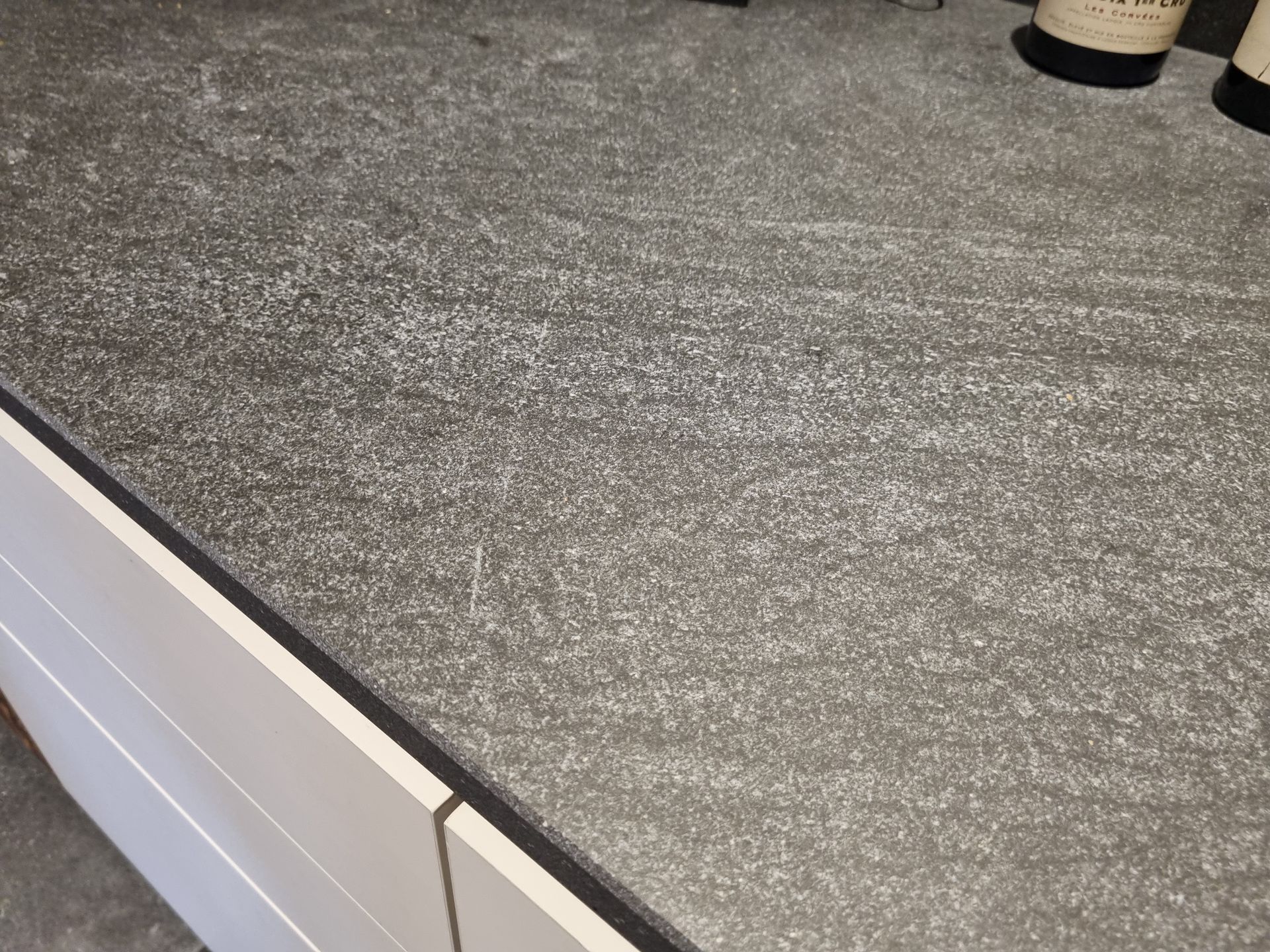 Plan de travail gris avec armoire blanche et garniture noire.