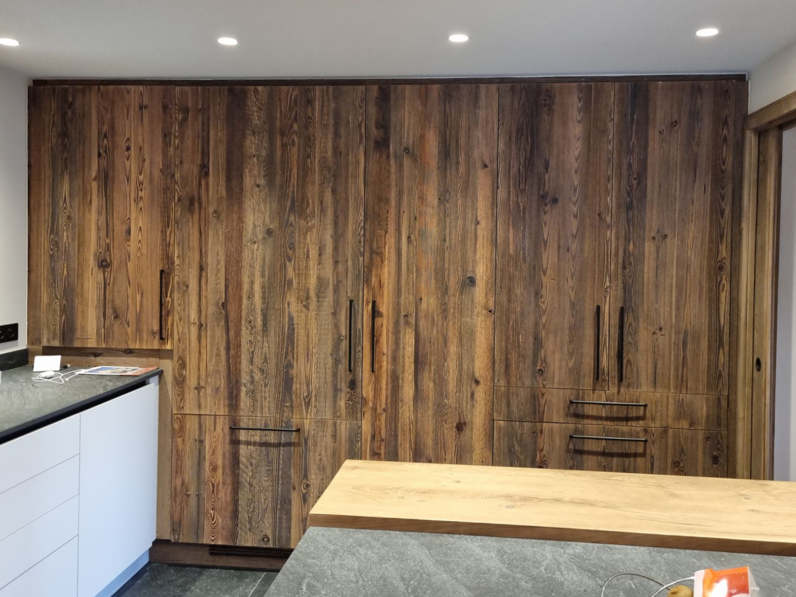 De grands placards rustiques en bois avec des poignées noires dans une cuisine.