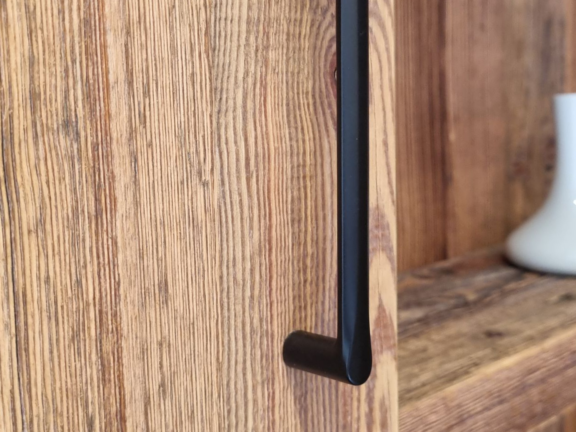 Poignée de meuble noire sur un meuble rustique en bois avec une étagère.