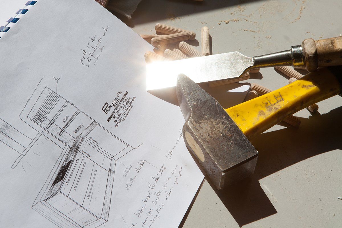 Plan avec outils de menuiserie : ciseau reflétant la lumière du soleil, marteau et chevilles en bois.