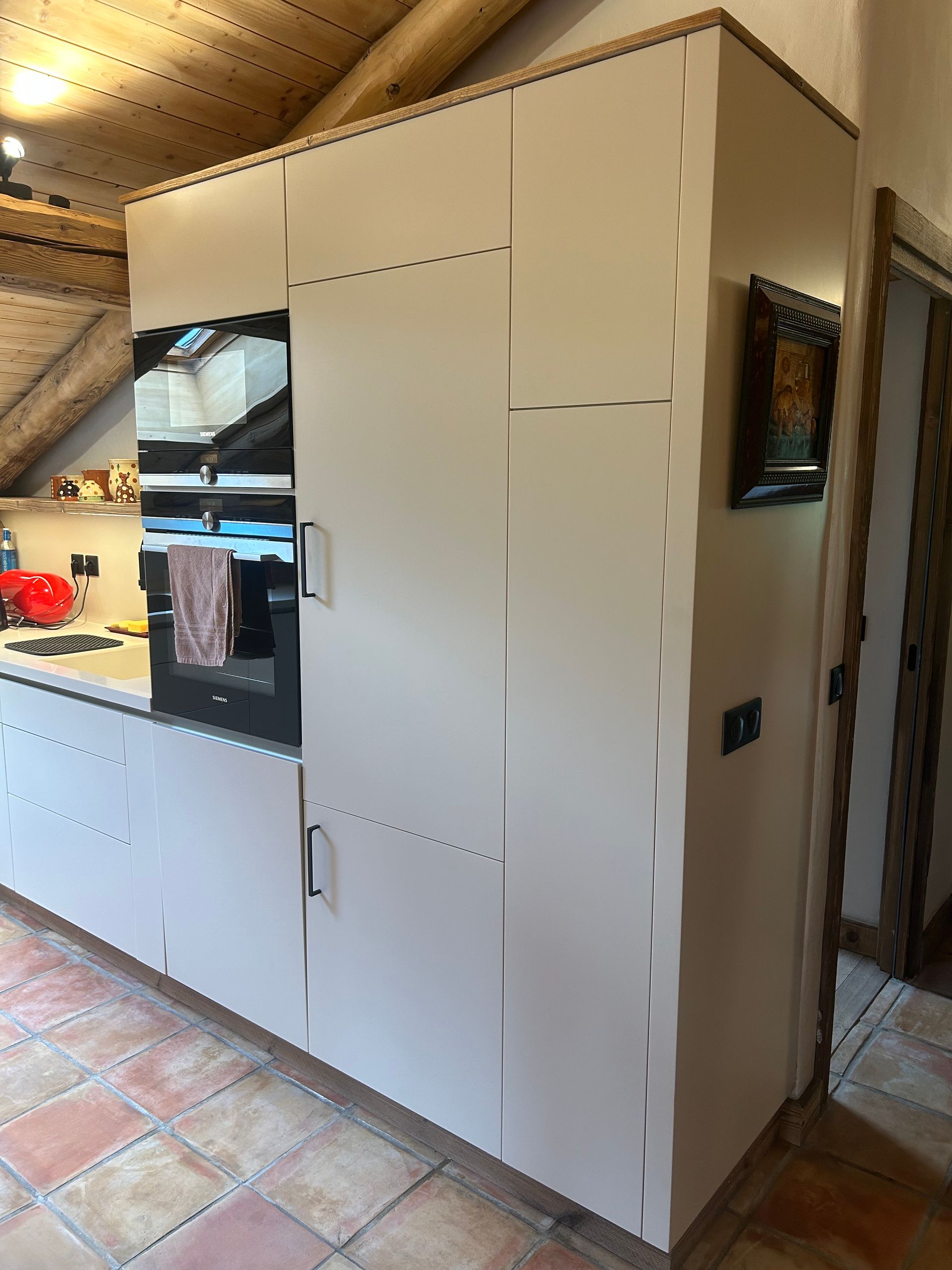 Cuisine moderne avec placards beiges intégrés au mur et four encastré.