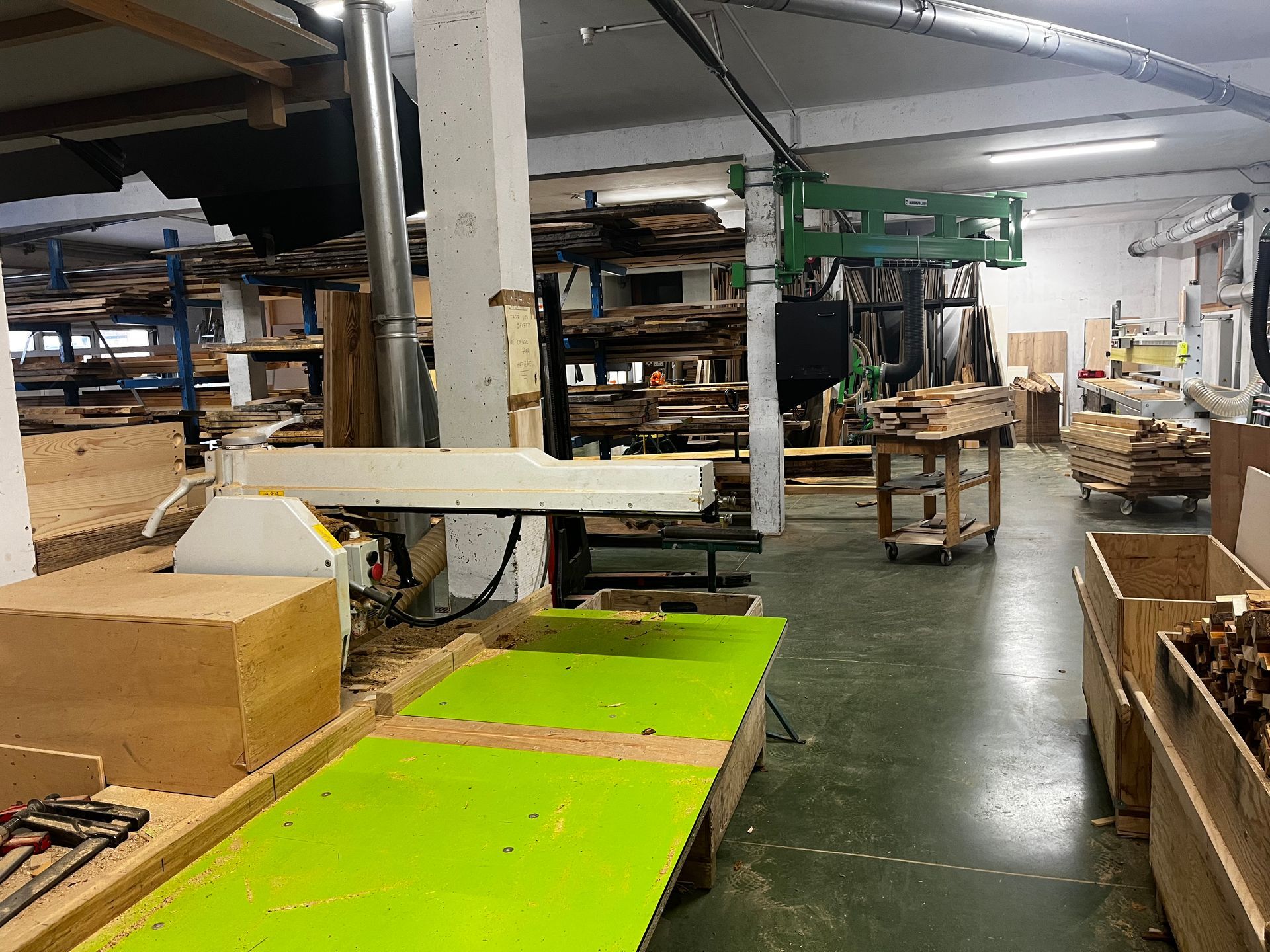 Atelier avec une table verte et des machines. Étagères en bois en arrière-plan.