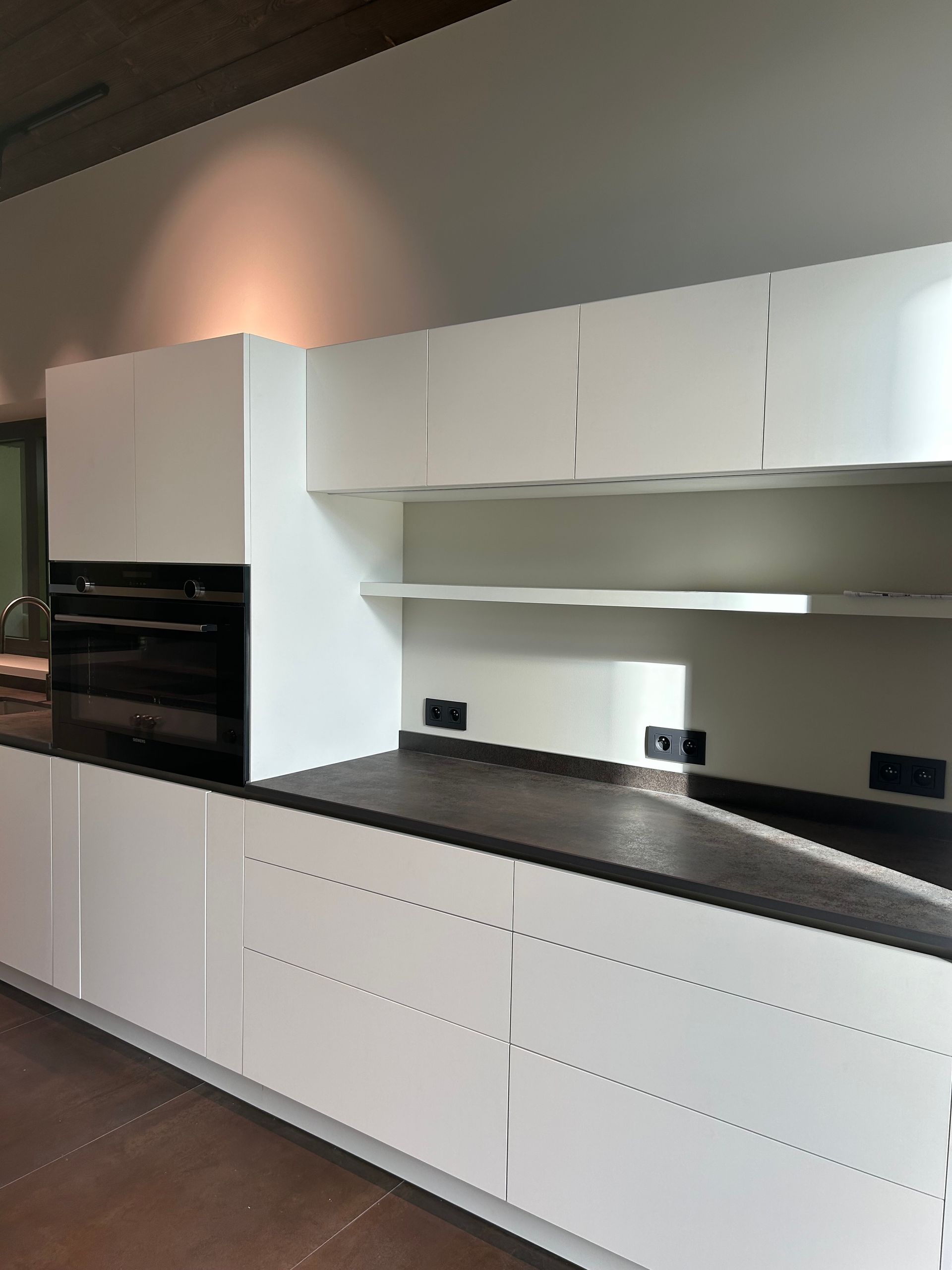 Cuisine avec placards blancs, comptoirs noirs et électroménagers intégrés.