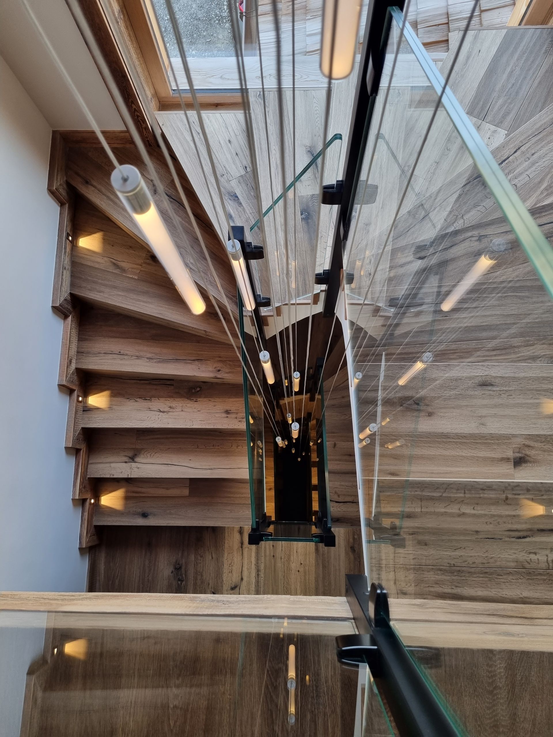 Escalier avec marches en bois et rambarde en verre. Vue aérienne. Luminaires.