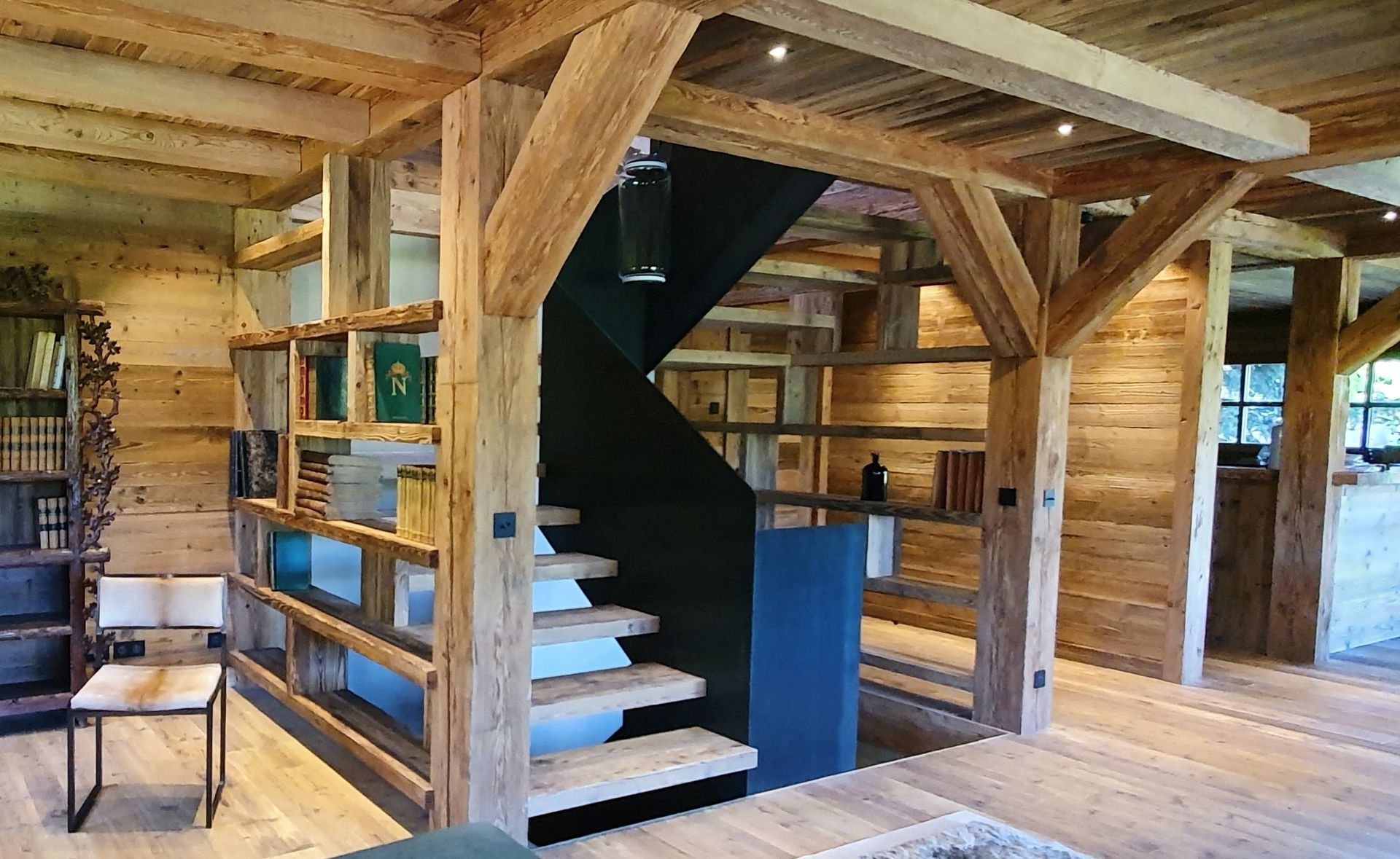 Intérieur rustique en bois avec un escalier noir et des bibliothèques intégrées.