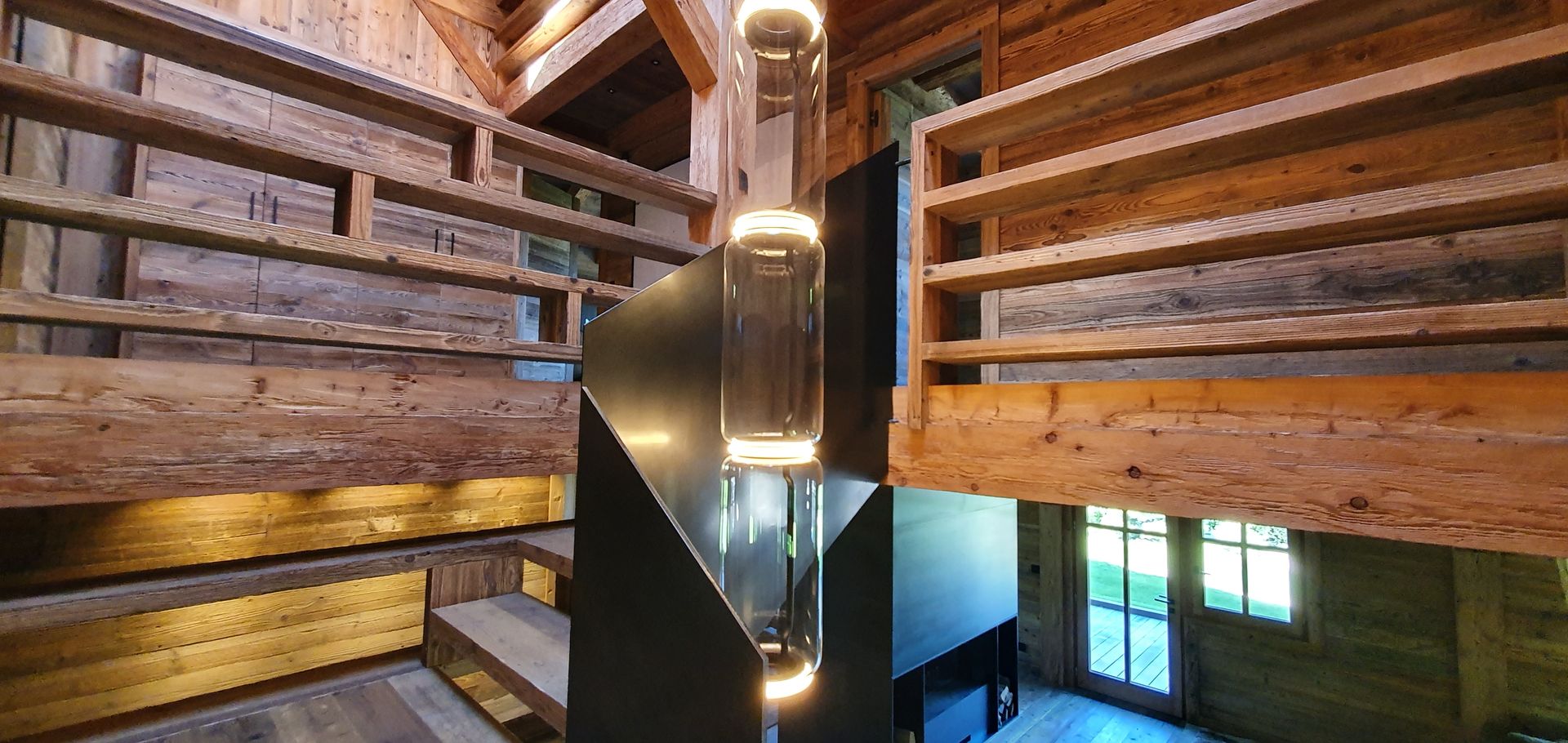 Vue intérieure d'une cabane en bois avec un escalier en colimaçon noir moderne et des étagères.