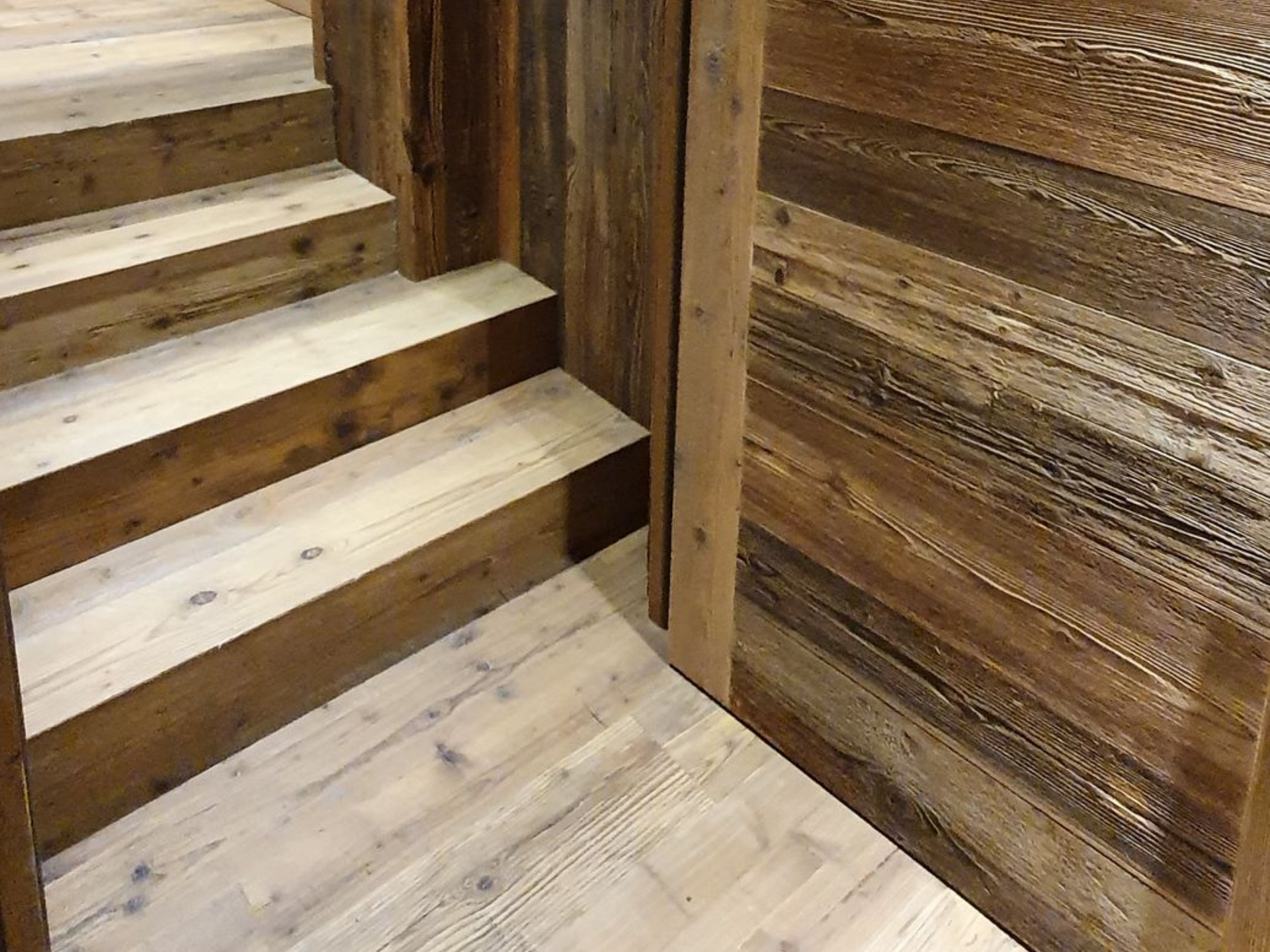 Porte coulissante en bois à panneaux diagonaux, ouverte sur un escalier.