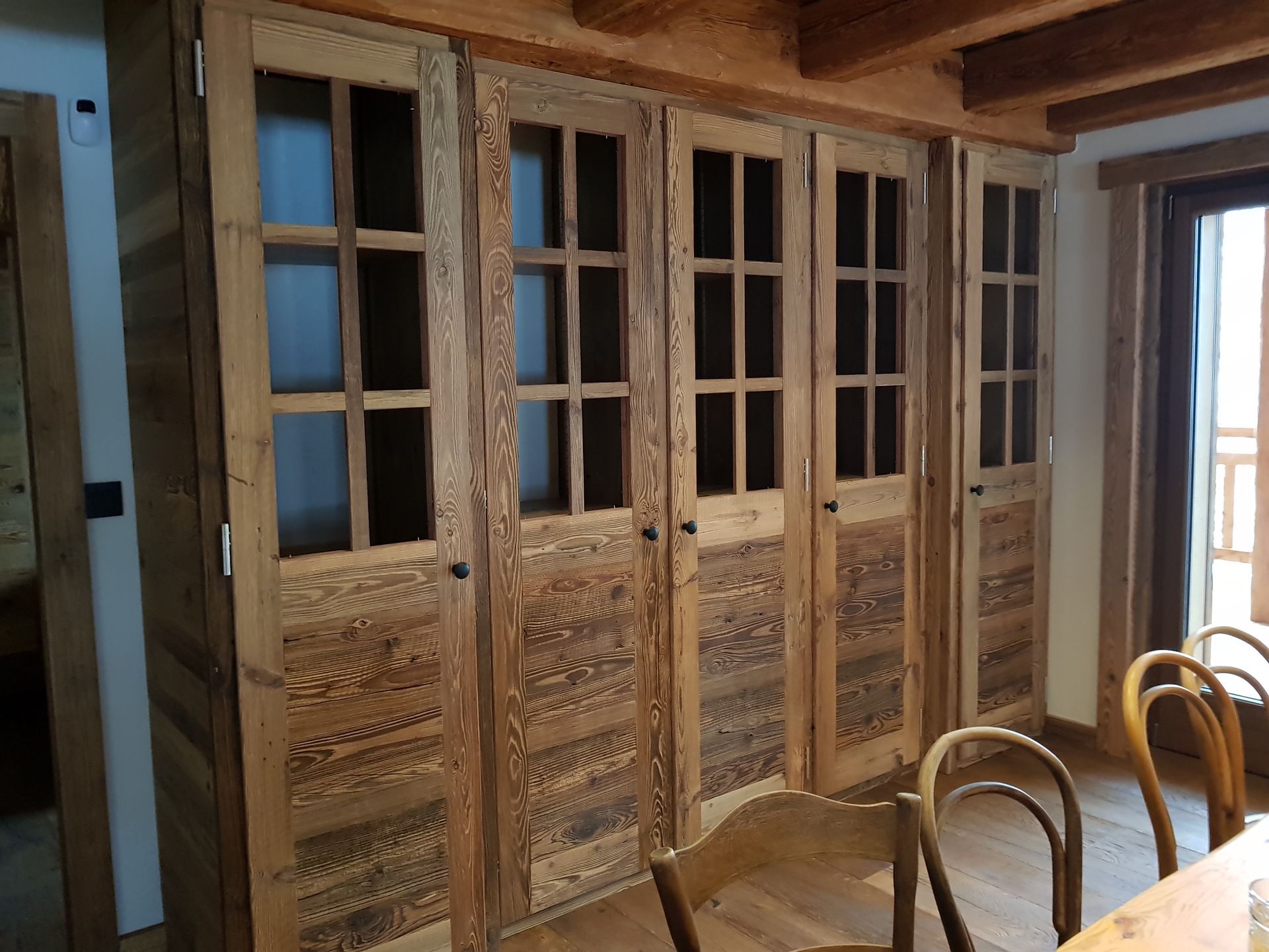 Armoires en bois avec portes vitrées, encastrées dans un mur rustique.