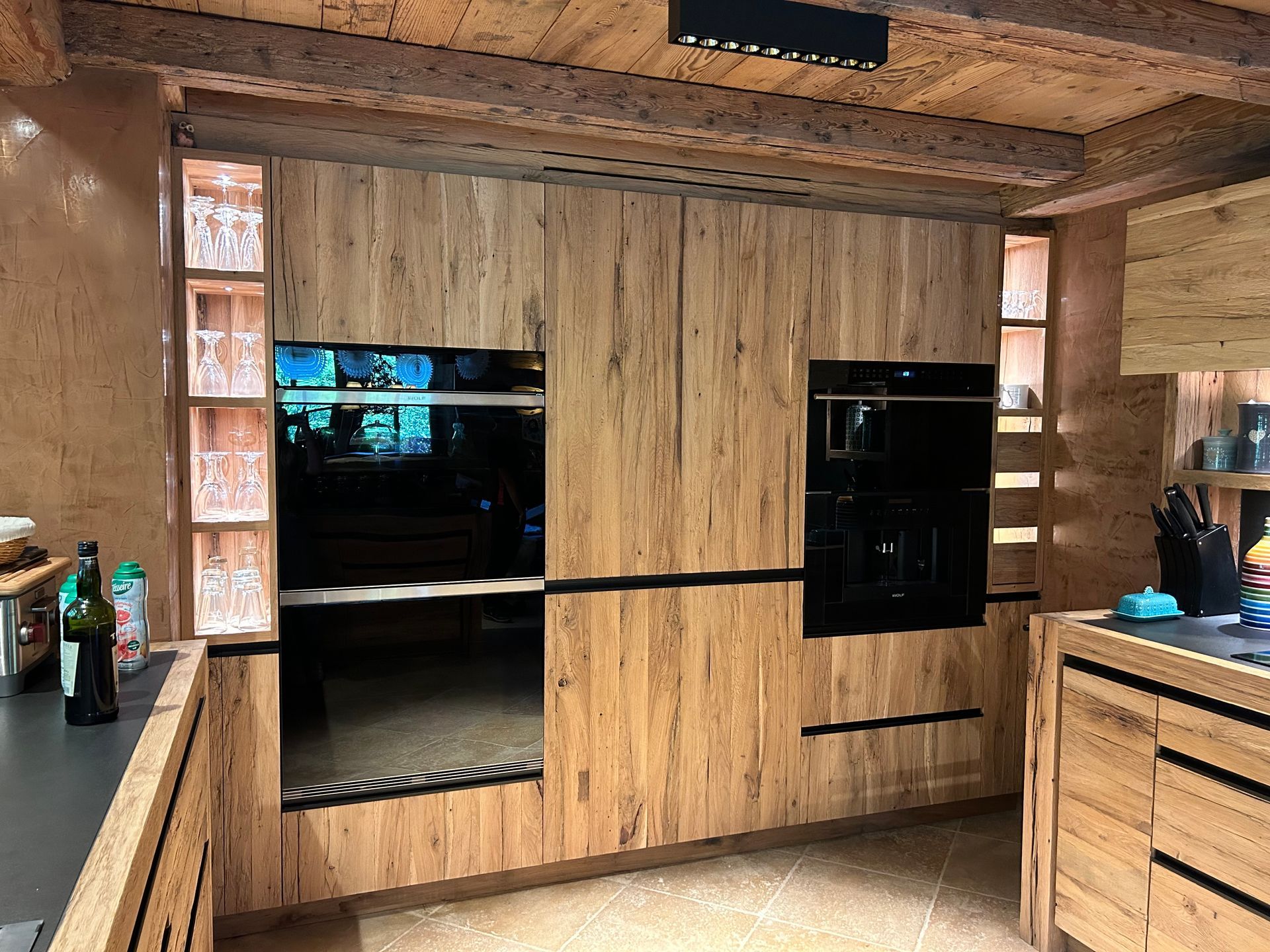 Cuisine équipée d'armoires en bois, d'appareils électroménagers intégrés et d'un éclairage encastré.