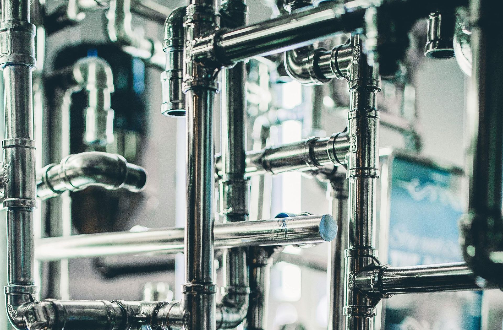 Shiny metal pipes forming a complex network, likely in an industrial or scientific setting.