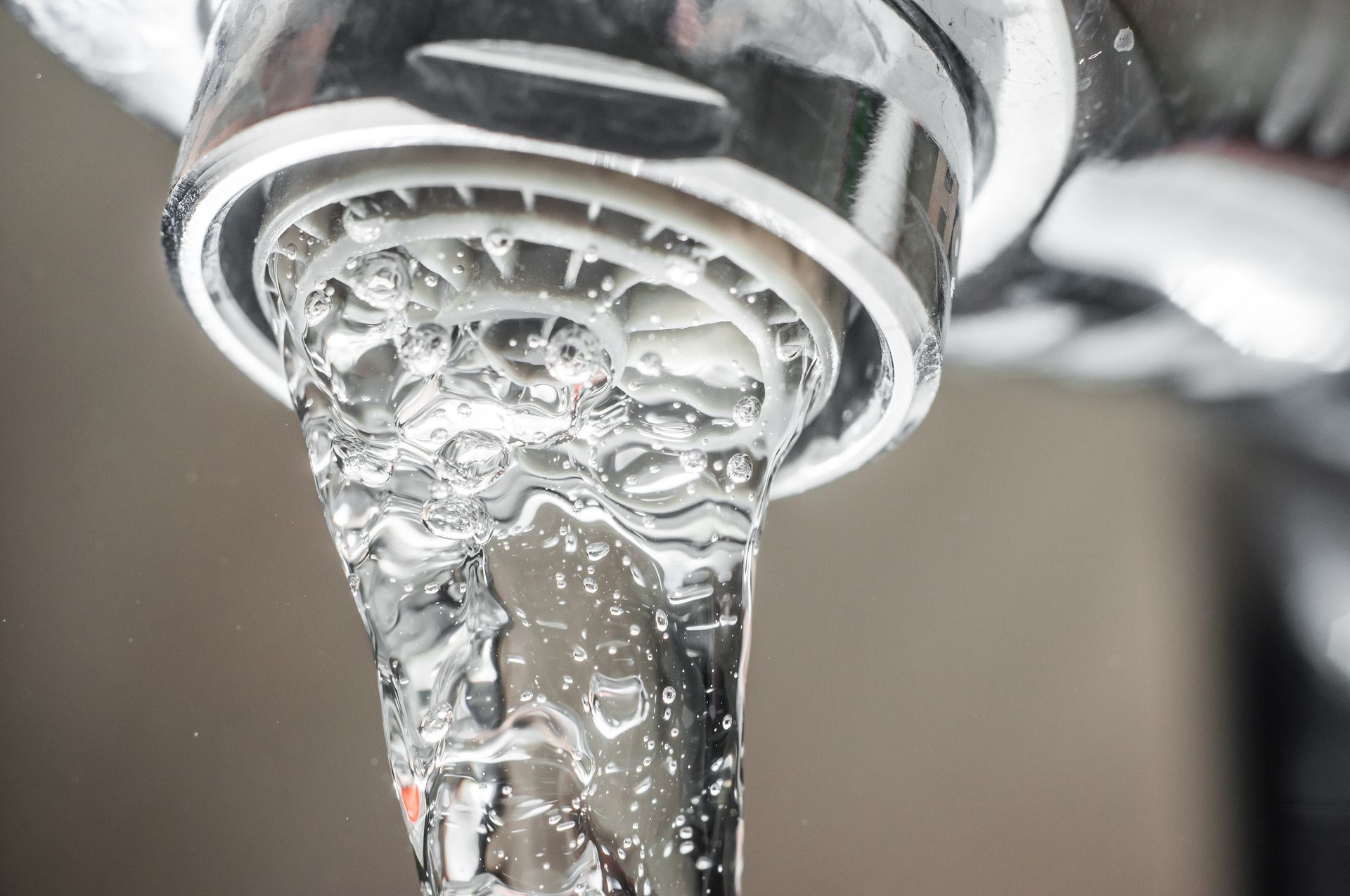 Close-up of chrome faucet with water flowing, creating bubbles and splashes.