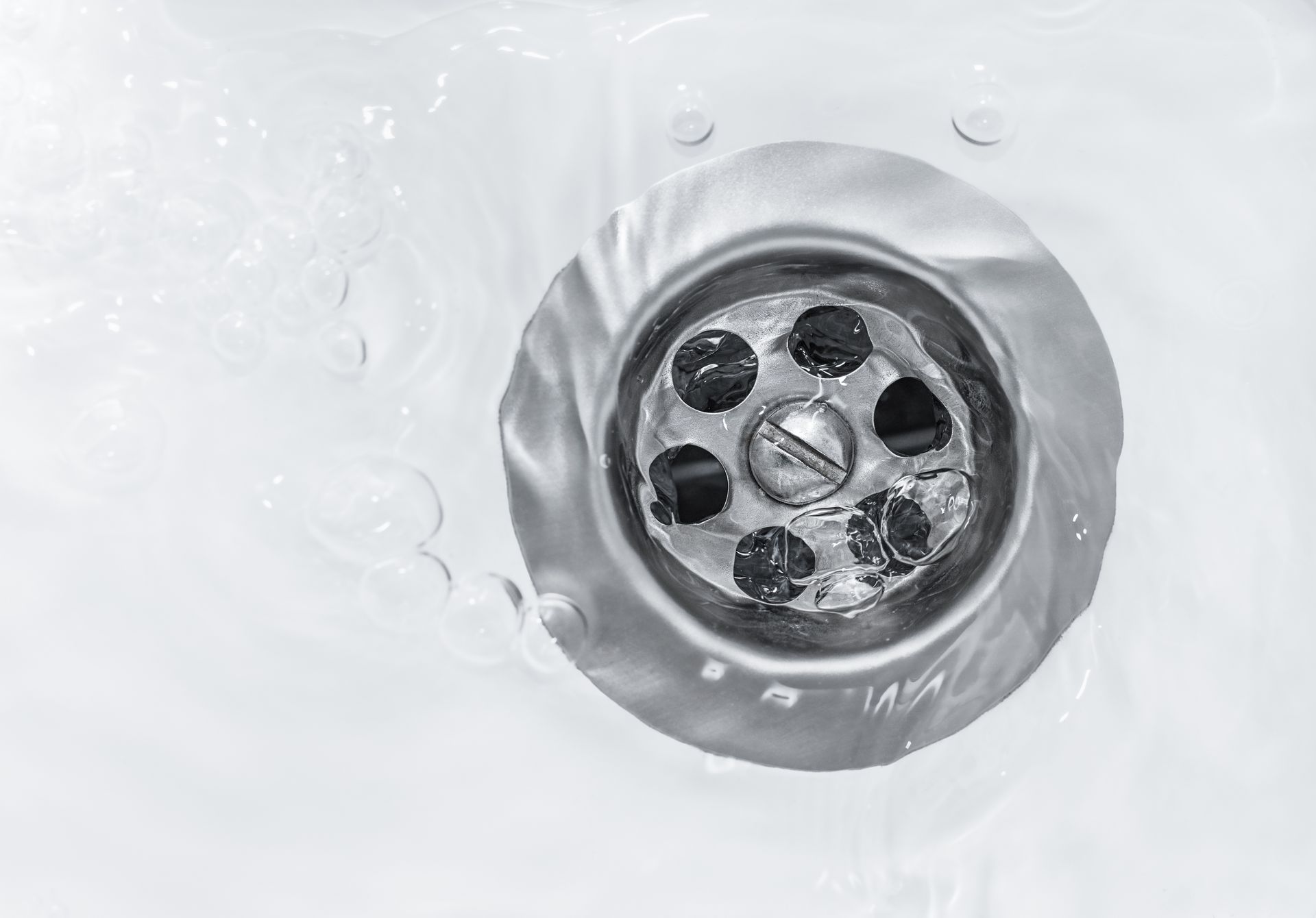 Water flowing into a stainless steel sink drain.