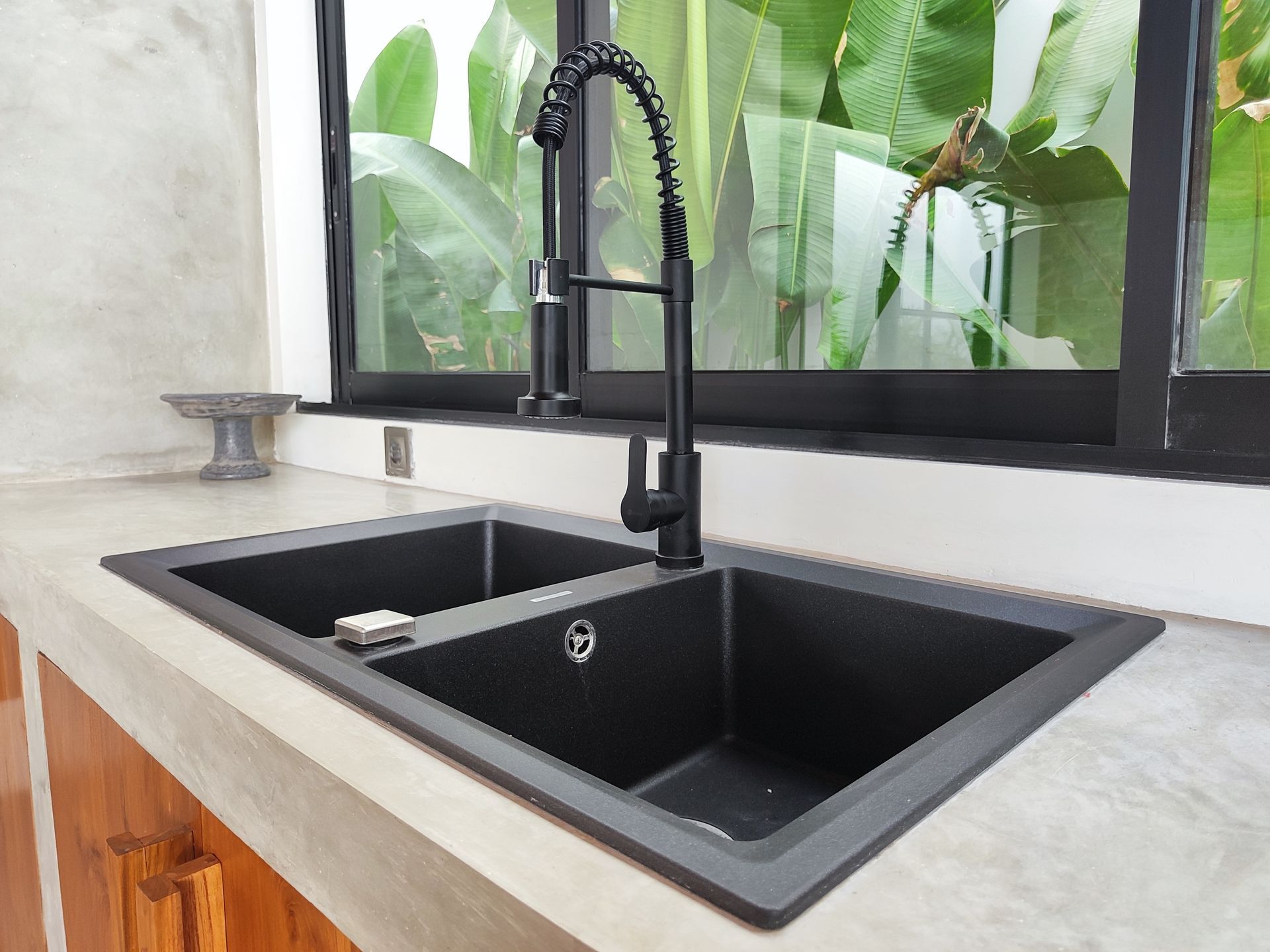 Black double kitchen sink with black faucet by a window, countertop.