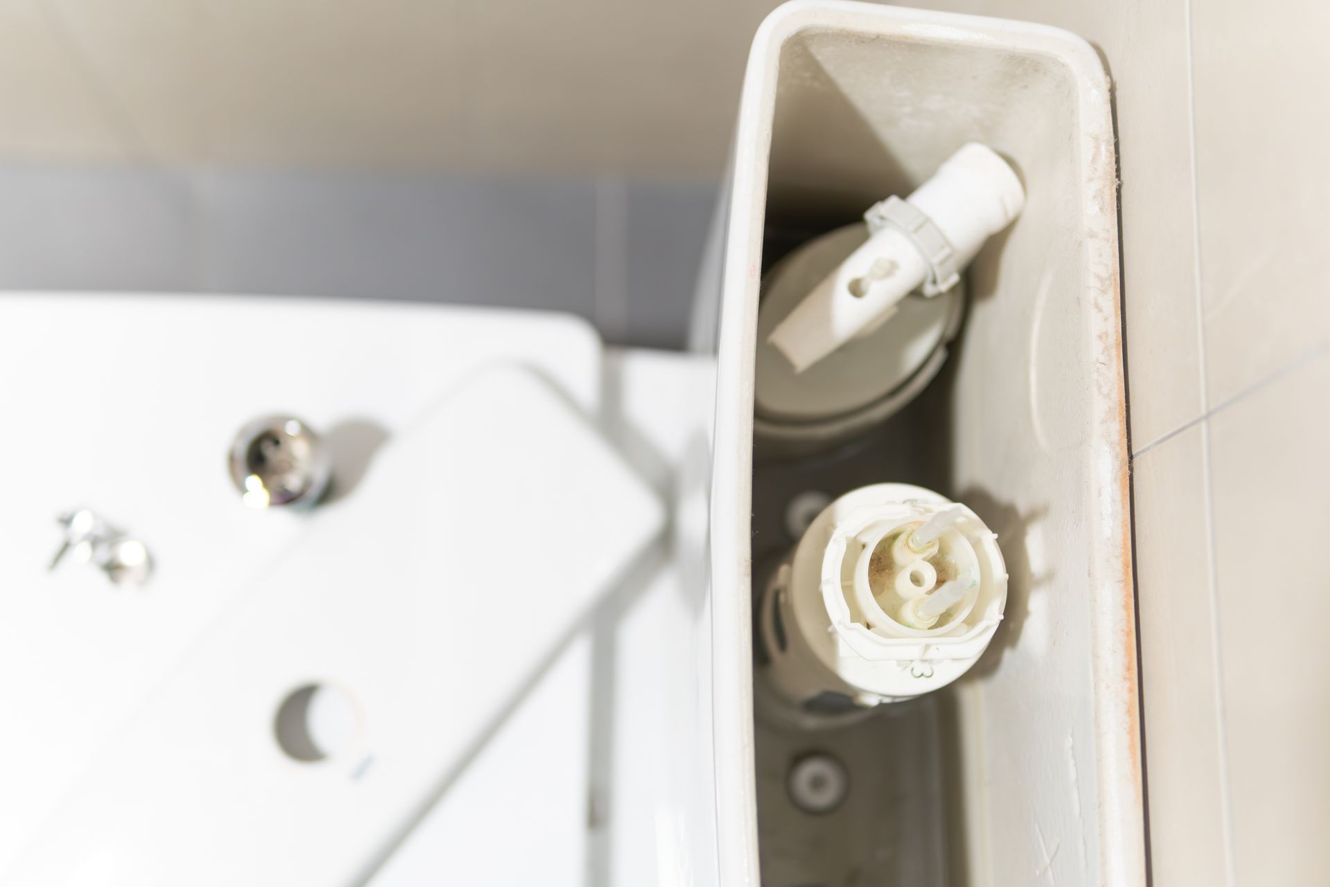 Toilet tank interior showing disassembled fill valve, flush valve, and associated components.