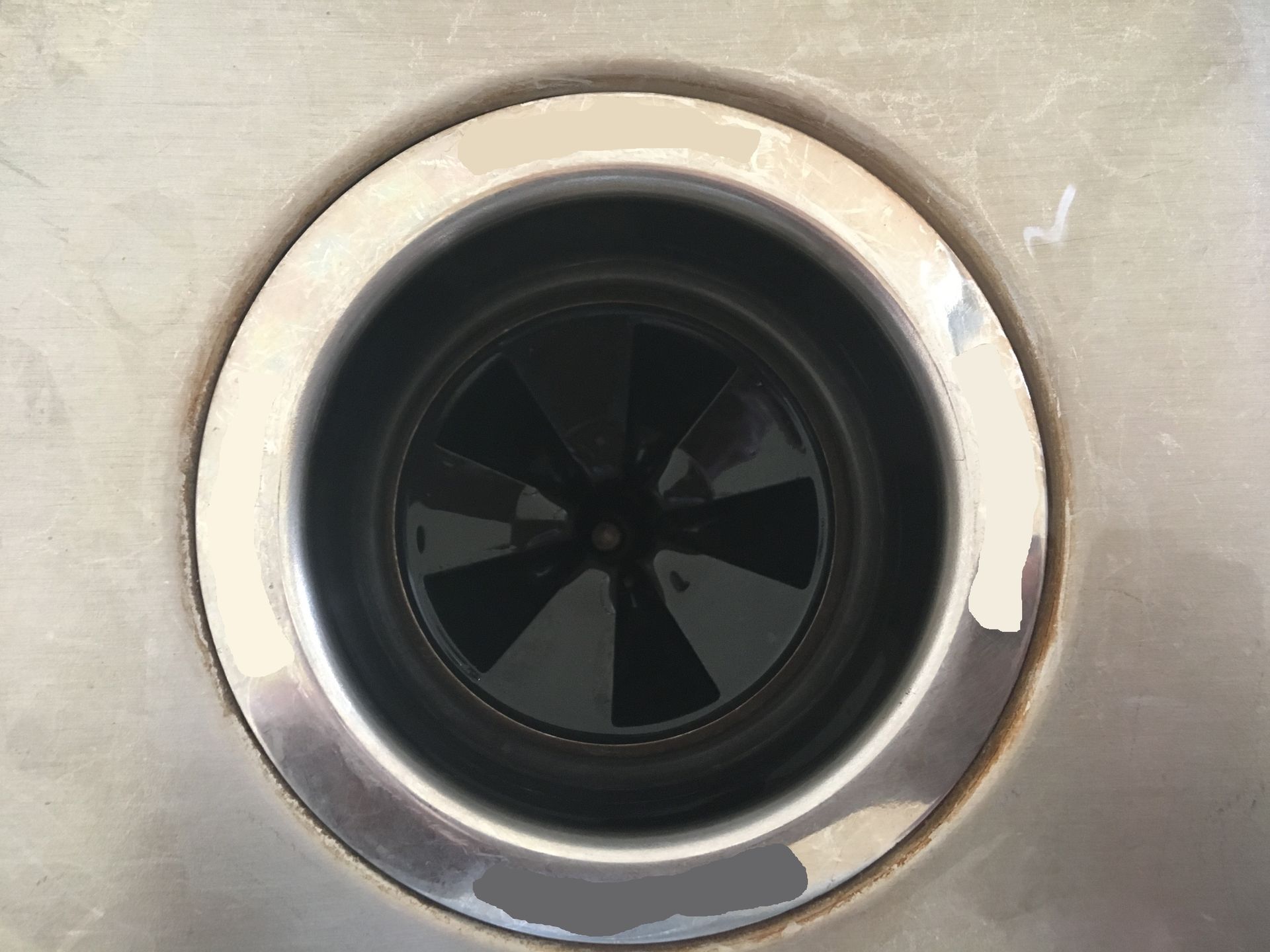 Stainless steel sink drain with a dark interior.