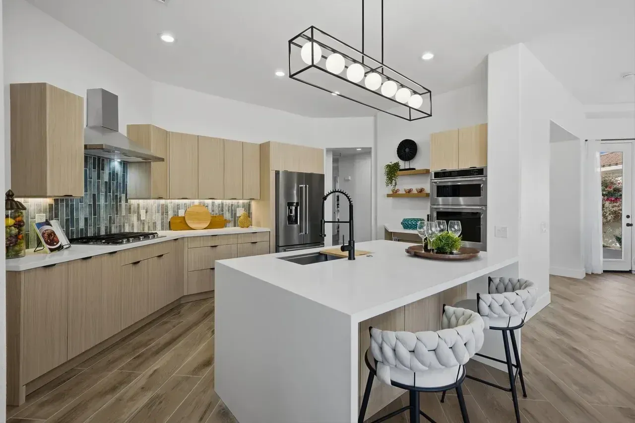 Modern kitchen with light wood cabinets, white island, and black faucet.