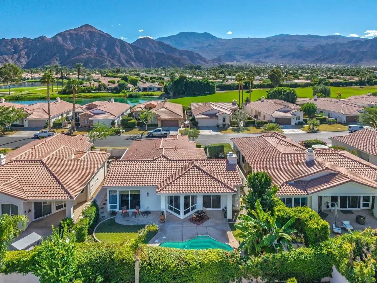 Houses with red tile roofs and swimming pool, with mountains in the background.