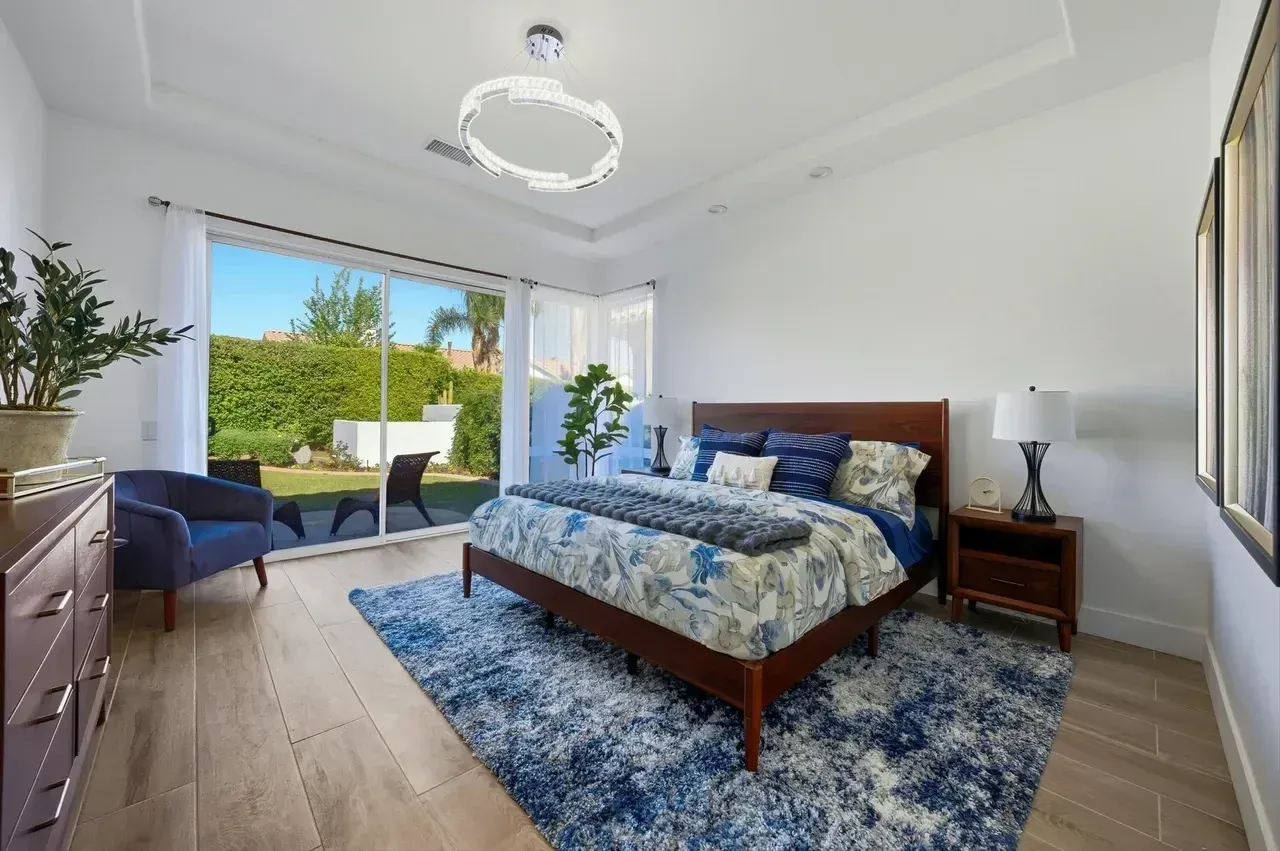 Bedroom with wooden bed, blue rug, and sliding glass door to a patio.