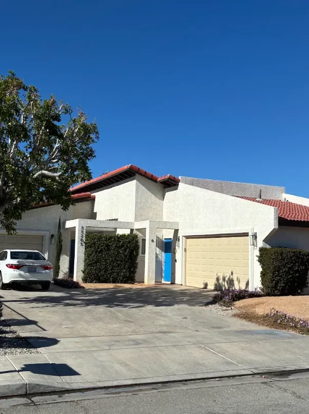 White house with blue door and beige garage door on a sunny day.