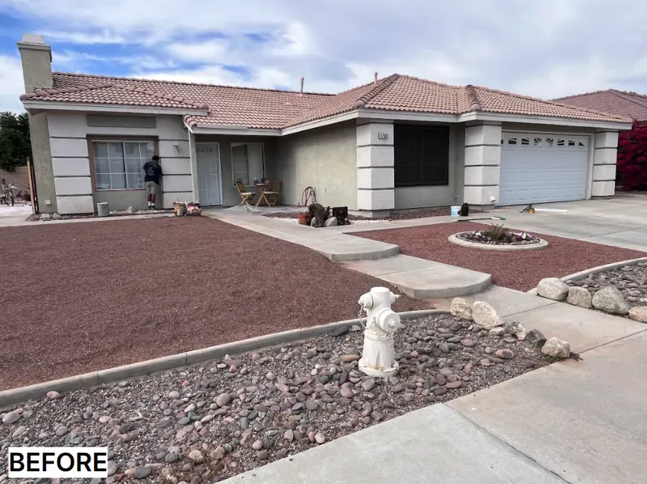 A beige one-story house before renovation; brown roof, red gravel yard, white garage door, concrete path