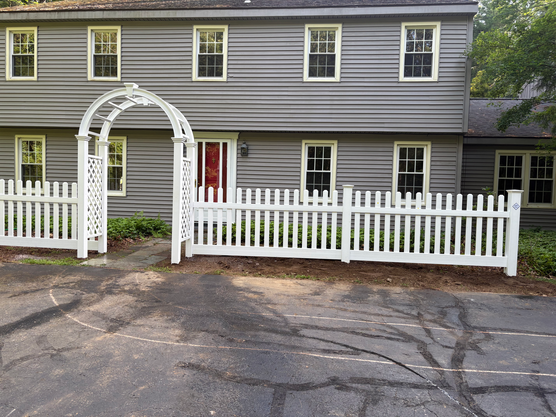 A white picket fence is in front of a gray house