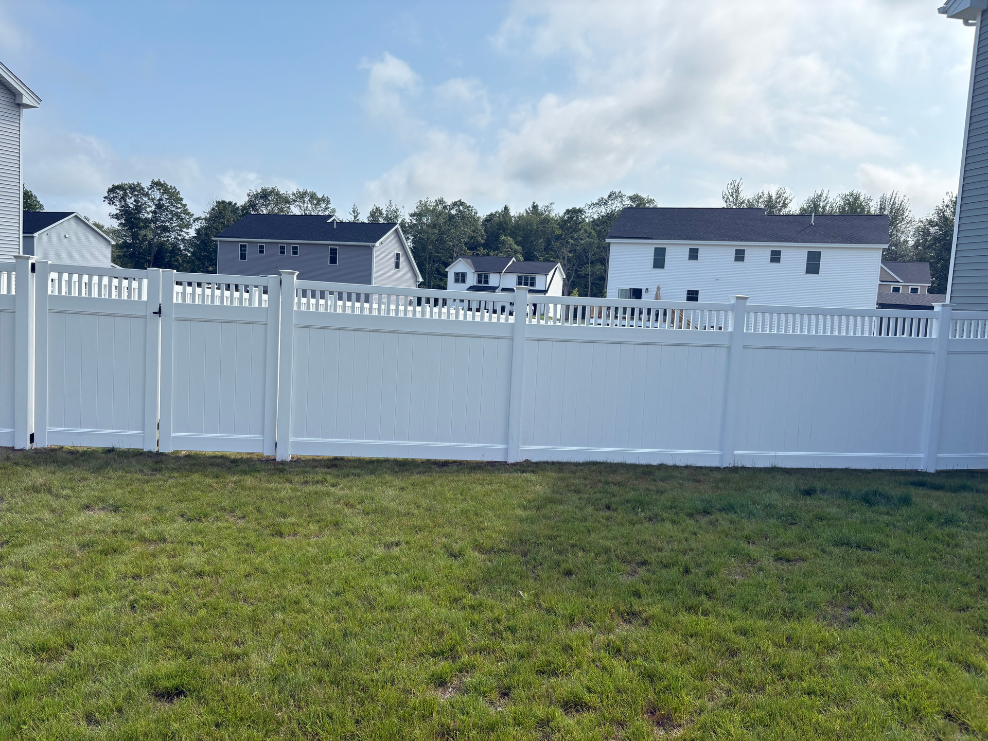 There is a white fence in the backyard of a house.