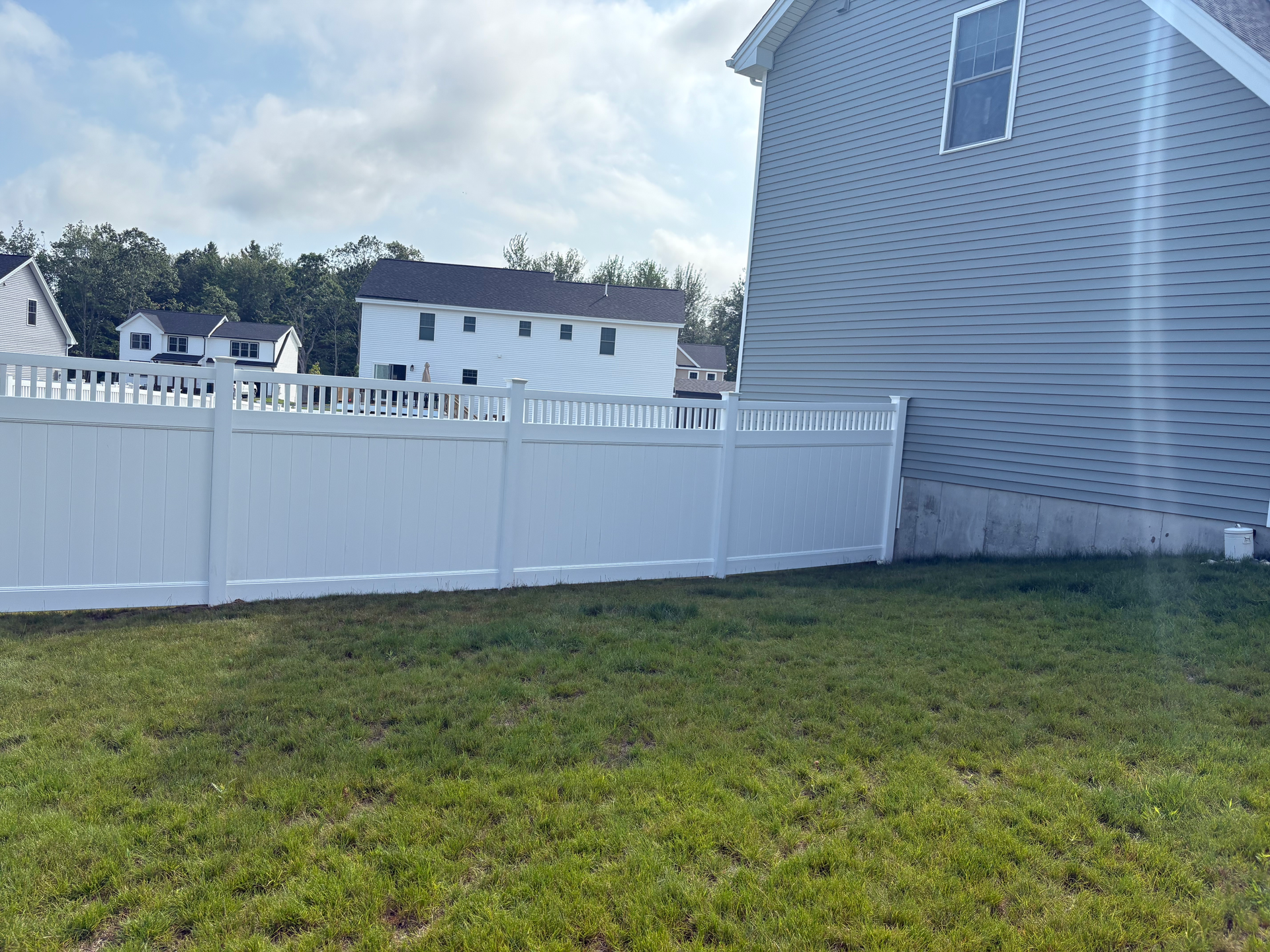 There is a white fence in the backyard of a house.