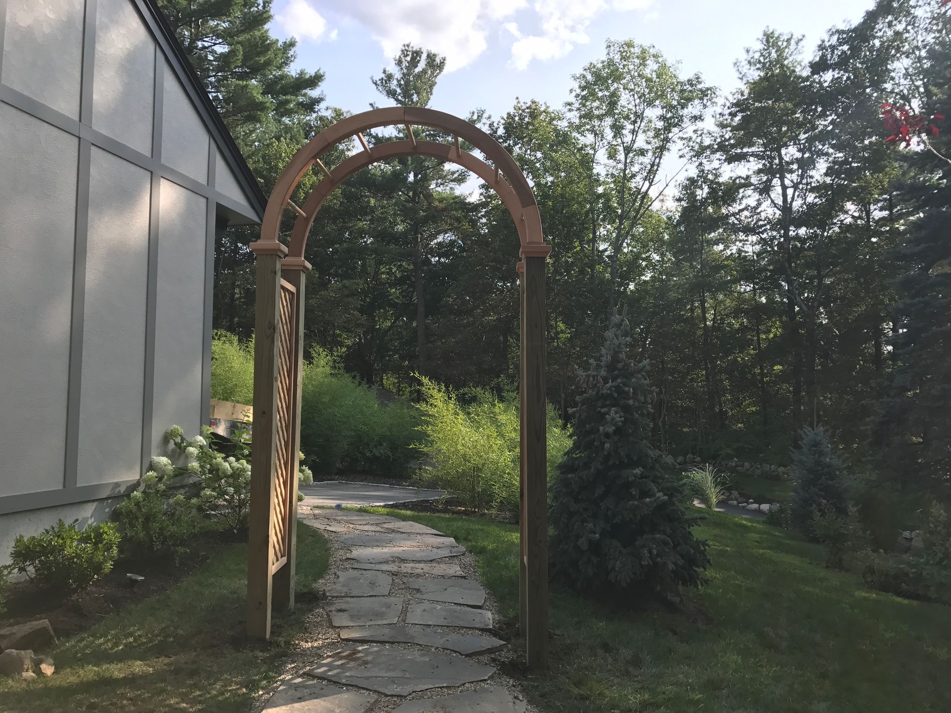 A wooden archway leading to a house in the woods