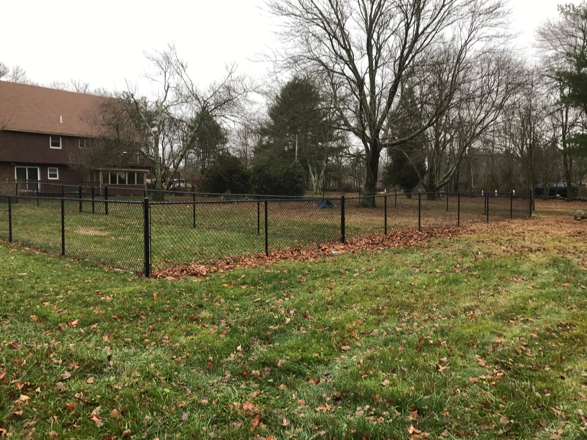 A large grassy field with a fence and a house in the background.