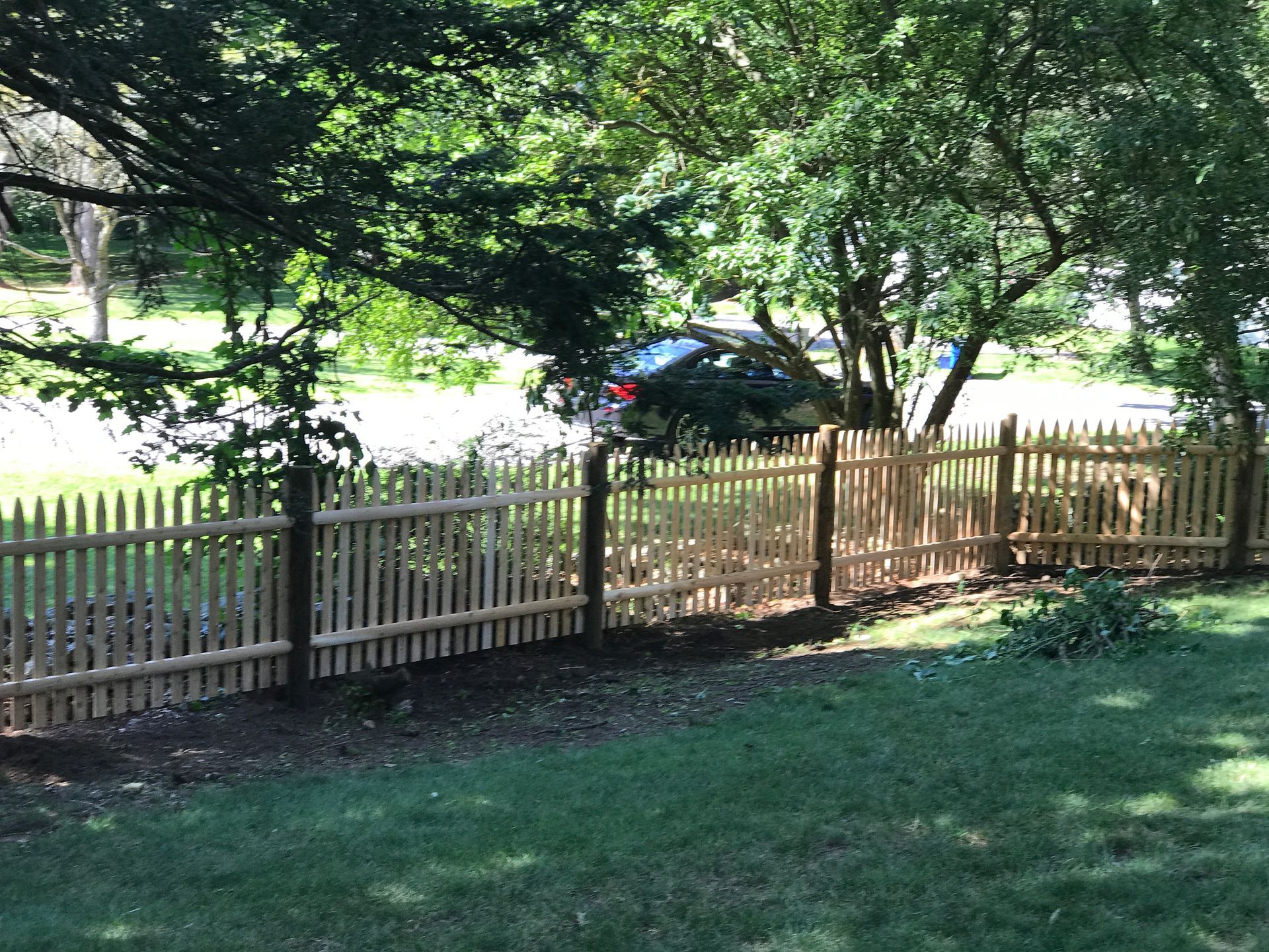 A wooden picket fence surrounds a lush green yard.
