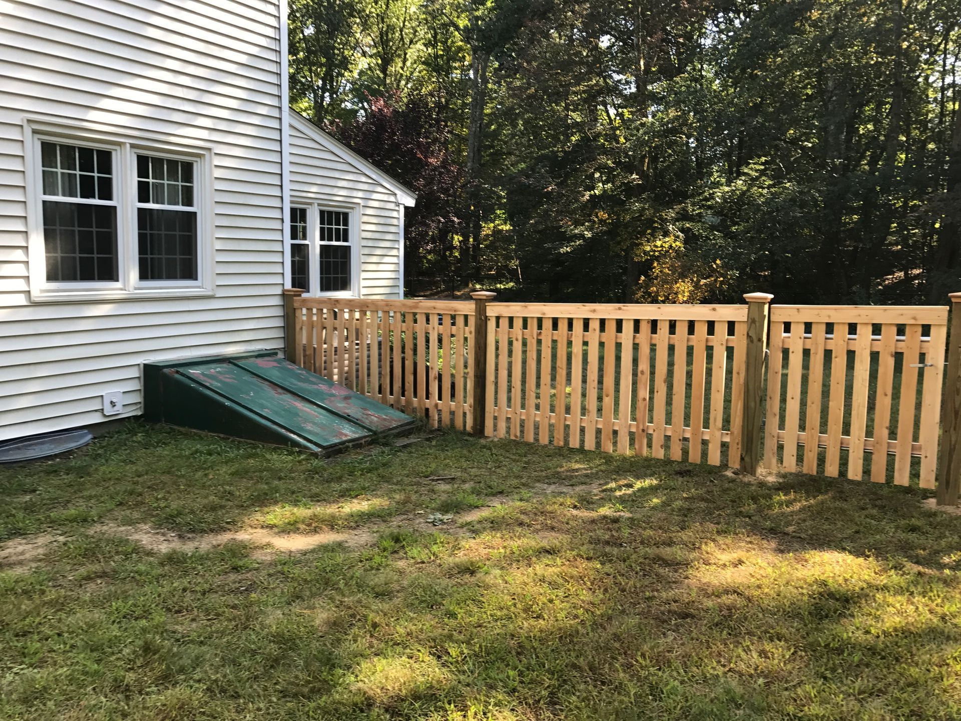 A wooden fence is in the backyard of a house.