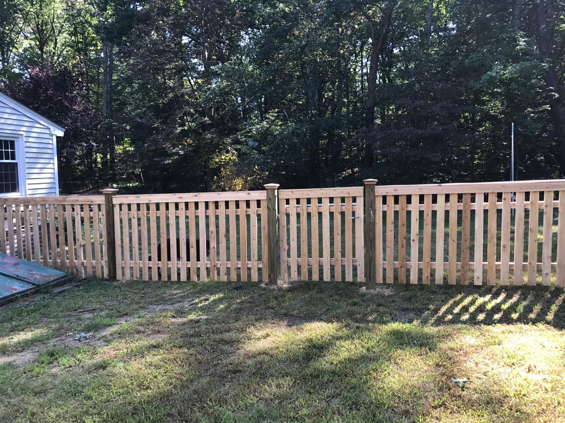 A wooden fence is in the backyard of a house.