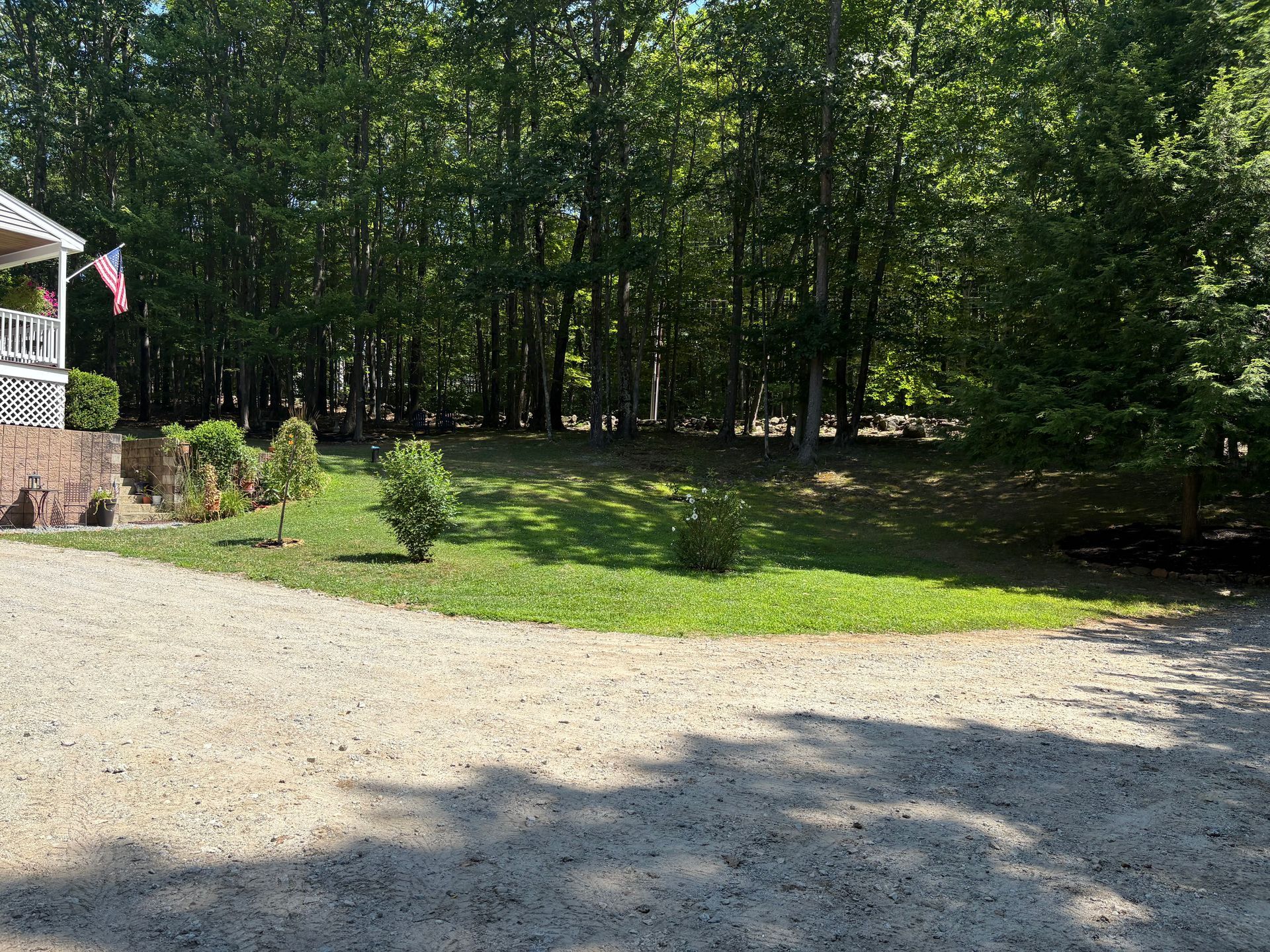 A house with a porch and a gravel driveway in front of it.