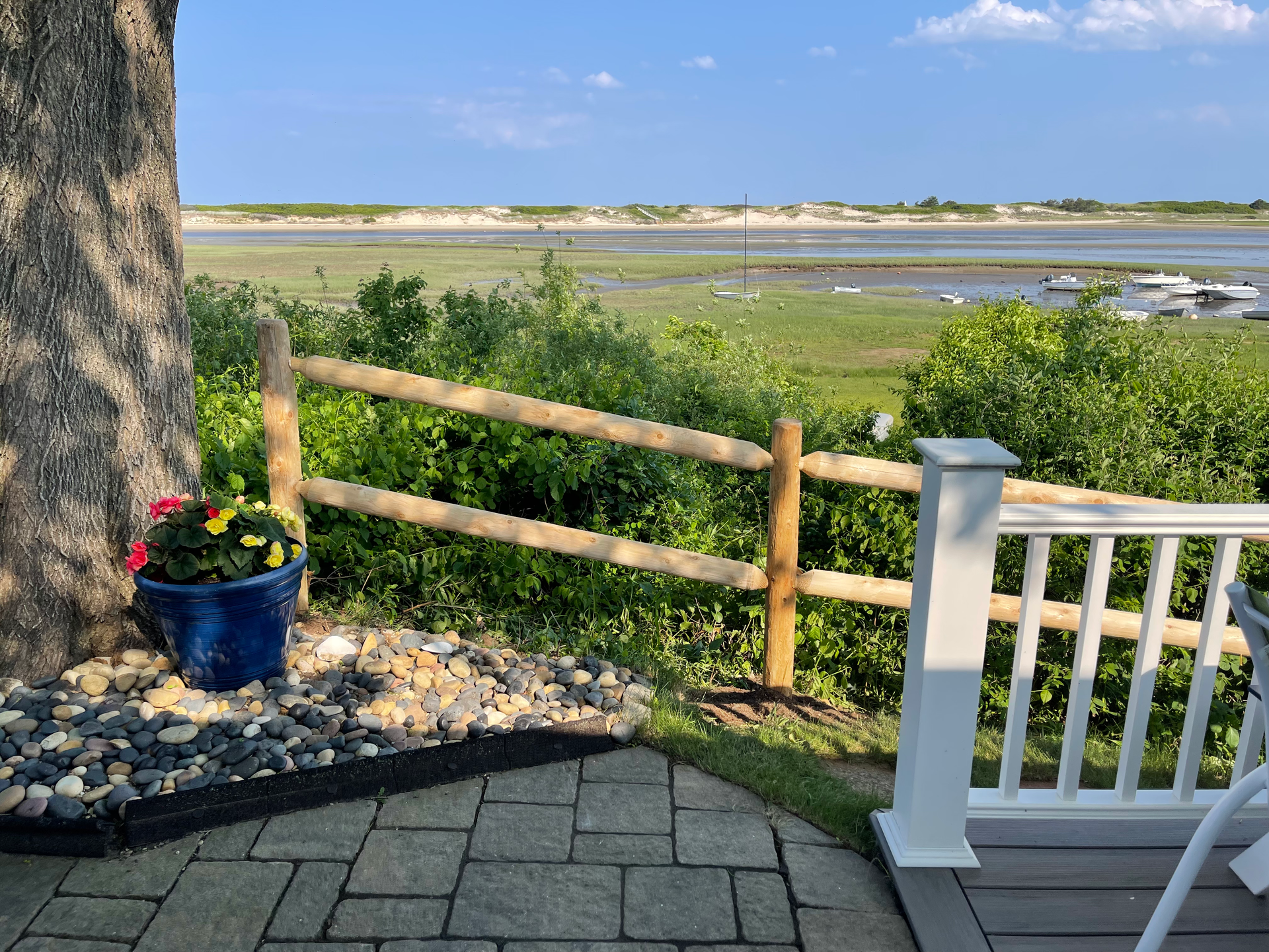A wooden fence surrounds a patio with a view of a body of water.