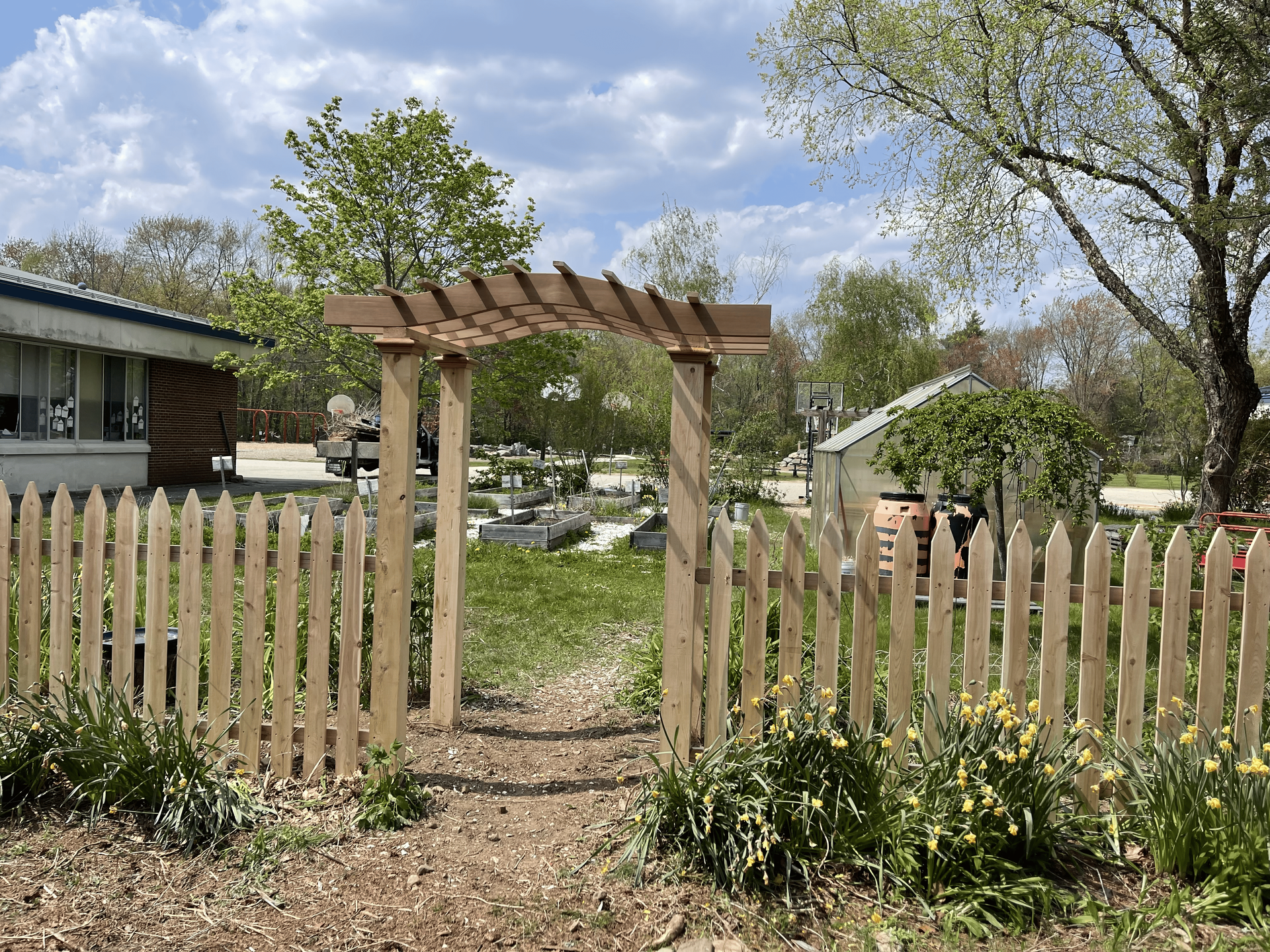 A wooden fence with a pergola in front of a house.