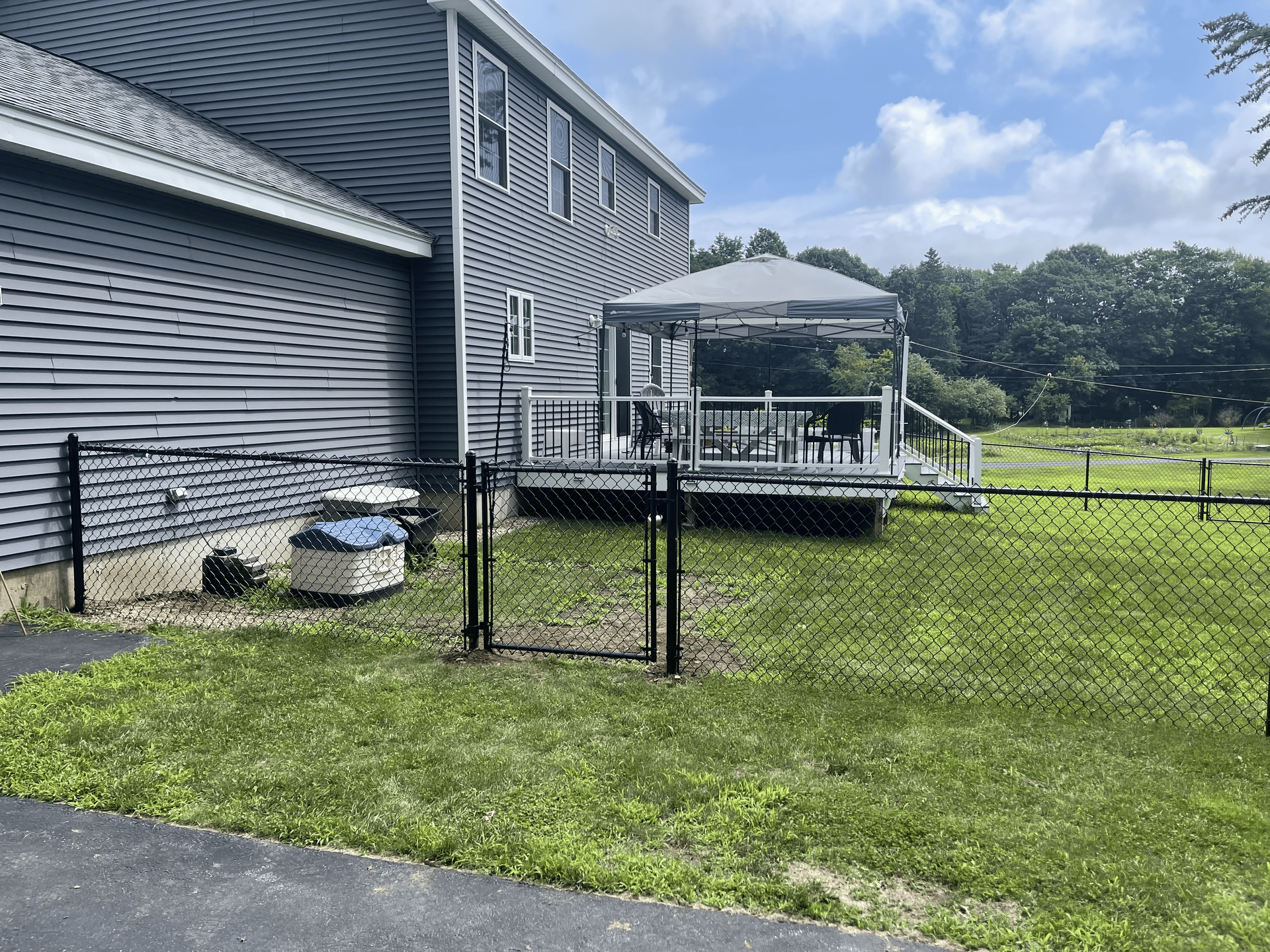 A house with a gazebo and a fence in front of it.